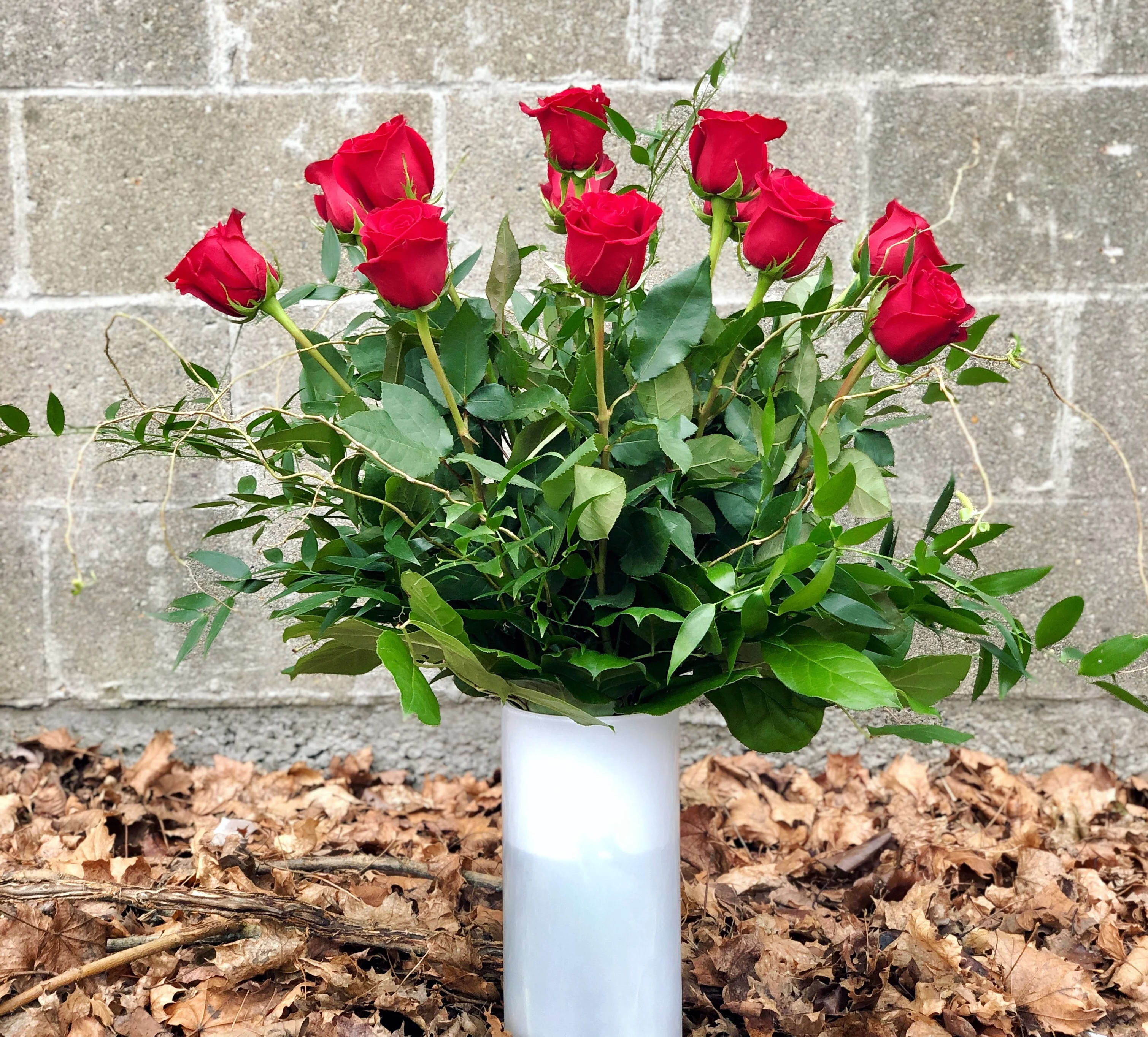 Red Roses in a Vase - Make a bold and romantic statement with our classic Red Roses in a Vase, beautifully arranged with lush, complementing greenery in a clear glass vase. Red roses are all about deep love, passion, and meaningful connection, making this arrangement a timeless choice for anniversaries, romantic gestures, or heartfelt expressions of love. Each design is handcrafted by our skilled designers using premium roses selected for their beauty and freshness.  Size Options: • Standard: One dozen red roses arranged in a vase • Deluxe: One and a half dozen red roses arranged in a vase • Premium: Two dozen red roses arranged in a vase  Please Note: To ensure the freshest roses possible, we purchase roses in limited quantities throughout the week rather than stocking large volumes. Because of this, same-day delivery is not automatically offered for this arrangement. However, same-day availability may be possible for red roses. If you are interested in same-day delivery, please call our shop and we’ll be happy to check availability for you.