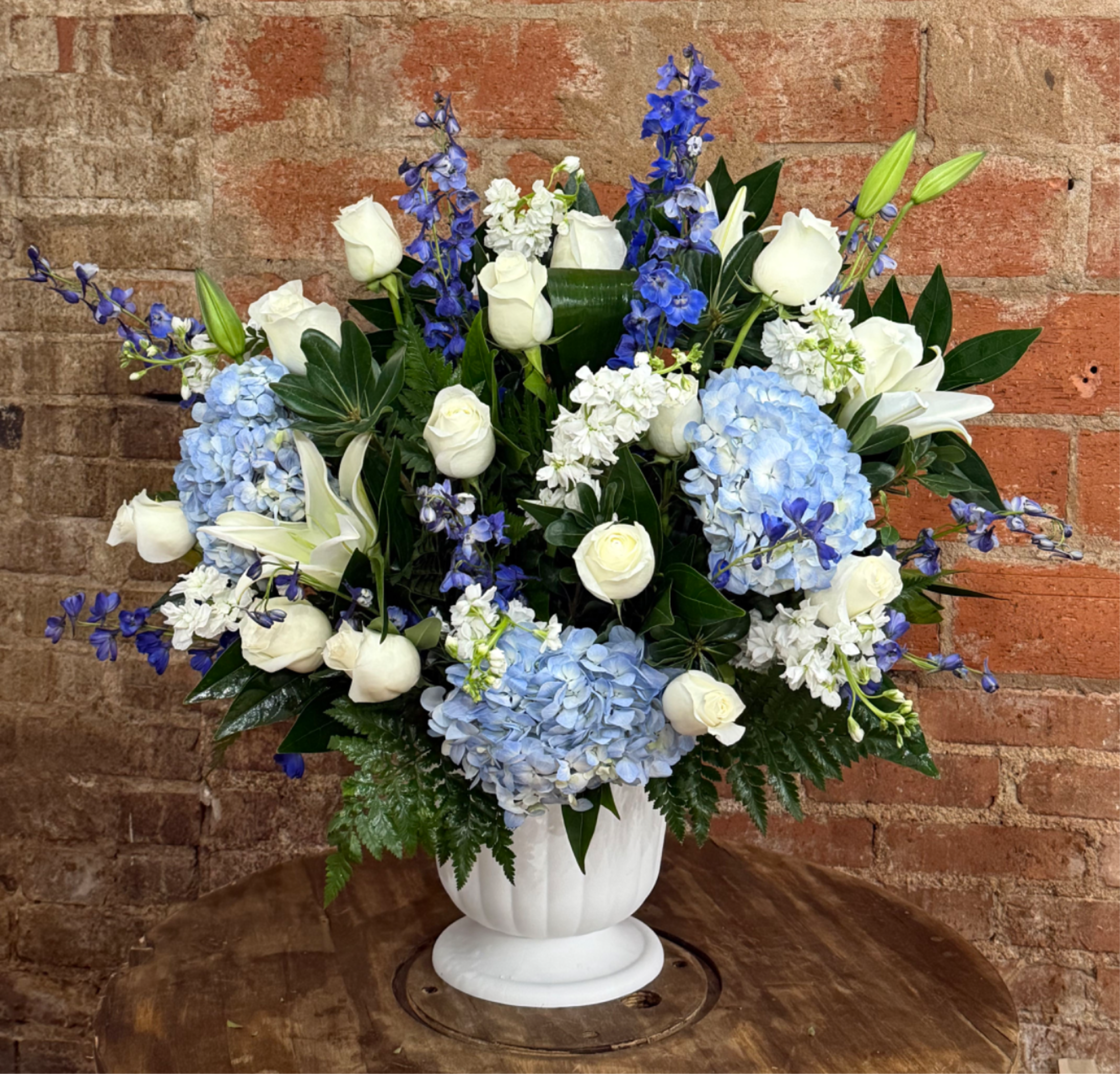 Designers Choice Sympathy Basket - Honor your loved one with a beautifully crafted urn basket, designed with the utmost care and creativity by our skilled florists. This personalized arrangement allows our designer free range to select the finest seasonal blooms and greenery, creating a unique tribute that reflects the essence and spirit of your cherished memory.  Each urn basket is thoughtfully arranged to provide a stunning display that complements the urn and serves as a heartfelt reminder of your loved one's life. With attention to detail and a focus on beauty, this arrangement offers a meaningful way to celebrate their memory and bring comfort to those who mourn.