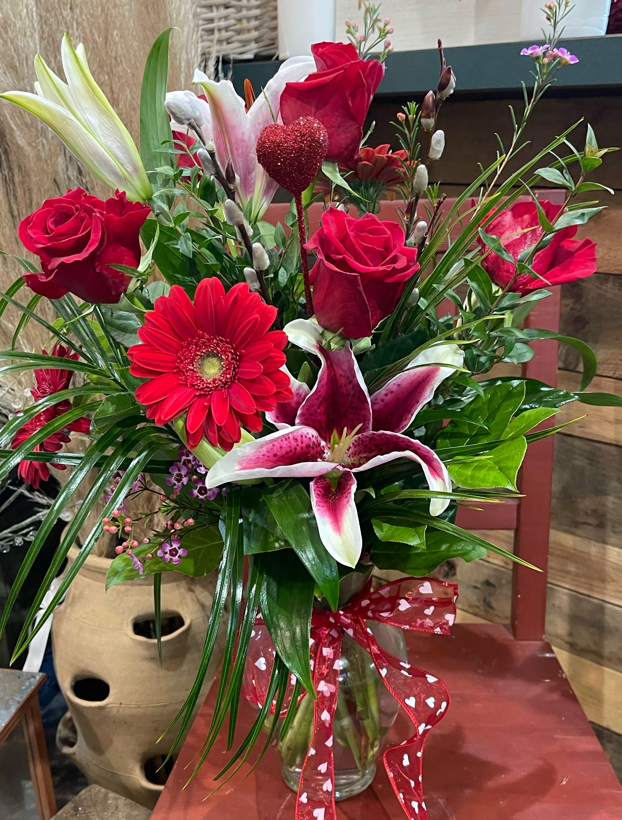 "Be Mine"   - Be Mine includes roses, lilies, gerber daises, and greenery. Arranged in a tall vase with a bow!