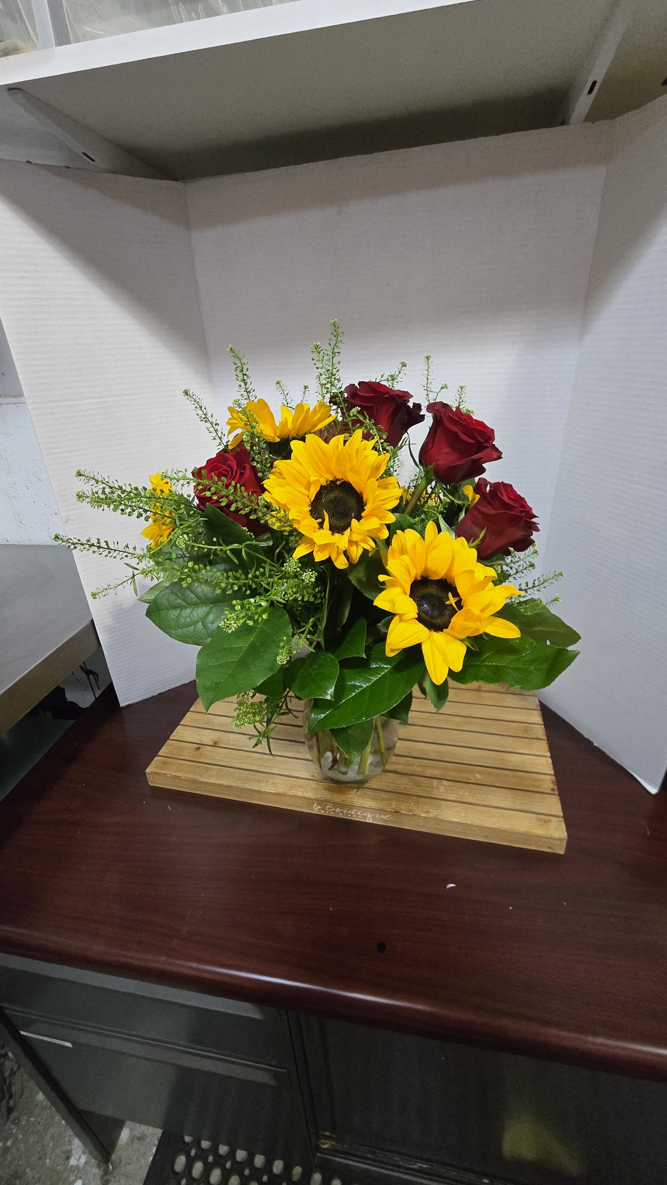 Romantic Sunshine   - An all around design of red roses, sunflowers and a mix of greens.  * Some stages of flower life may vary. (Example: Lilies may be more open than imaged.) Flower shortages and product availability means that some substitutions will apply. Value will always be filled. This bouquet might include eucalyptus amongst the greenery. It may be toxic to pets including but not limited to cats and dogs if digested.