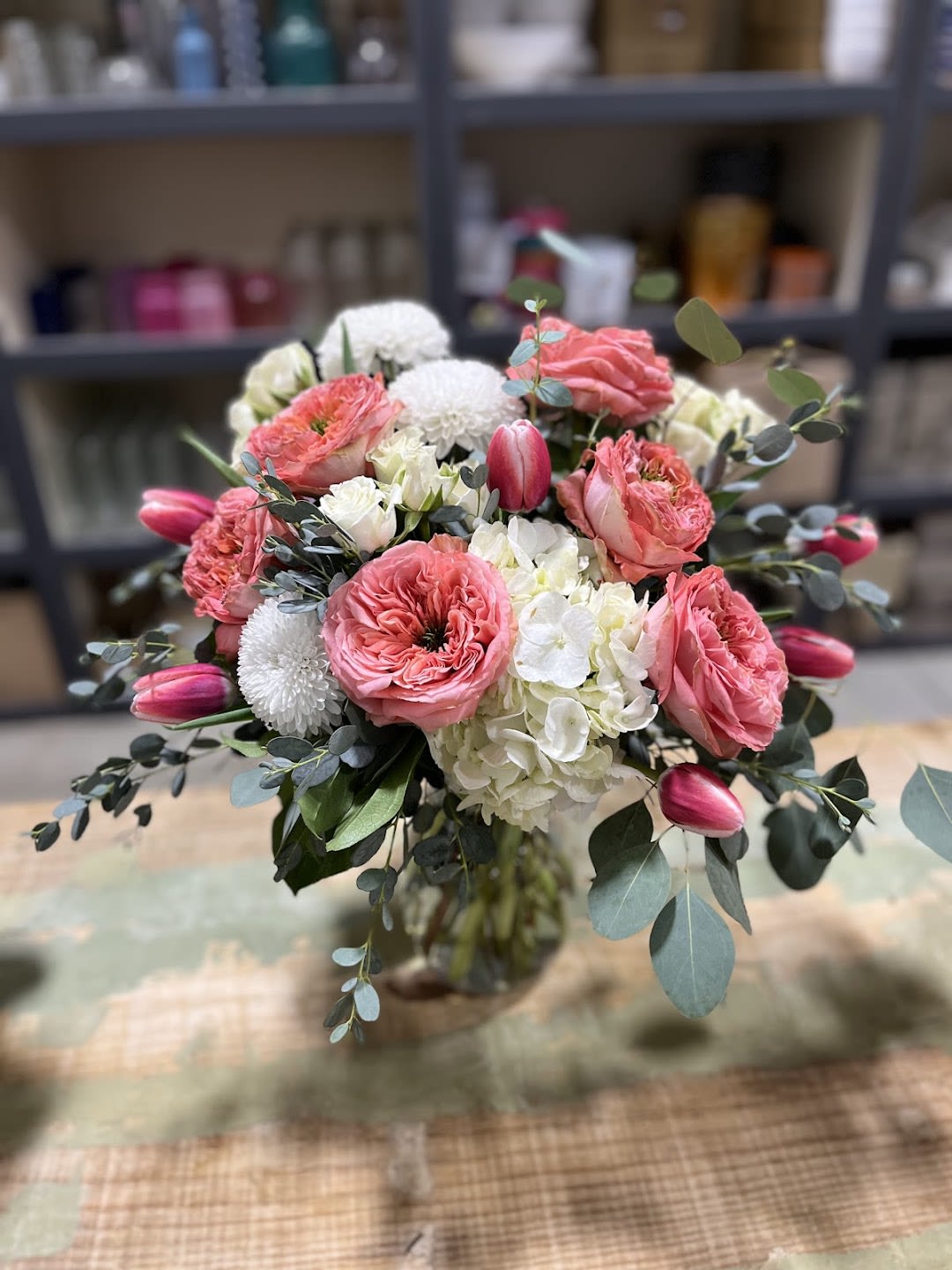 Blushing Meadow - Blushing Meadow is where effortless beauty meets gentle romance.  This lush, garden-style arrangement features layers of soft coral garden roses, delicate white hydrangea, creamy blooms, and fresh eucalyptus, accented with tulips and textured florals for a naturally gathered look. The color palette blends warm blush tones with crisp whites and fresh greenery, creating a design that feels both refined and inviting.  Designed in a clear glass vase, this arrangement brings a sense of calm luxury to any space — perfect for birthdays, thank-yous, celebrations, or simply brightening someone’s day.  Elegant without feeling formal, Blushing Meadow is a signature Adorkable Flowers piece: thoughtful, charming, and beautifully styled.  If you'd like, I can also make: • A shorter version for social media • A more romantic version • A more playful “adorkable” toned version  “**Blushing Meadow** is where effortless beauty meets gentle romance. This lush, garden-style arrangement features layers of soft