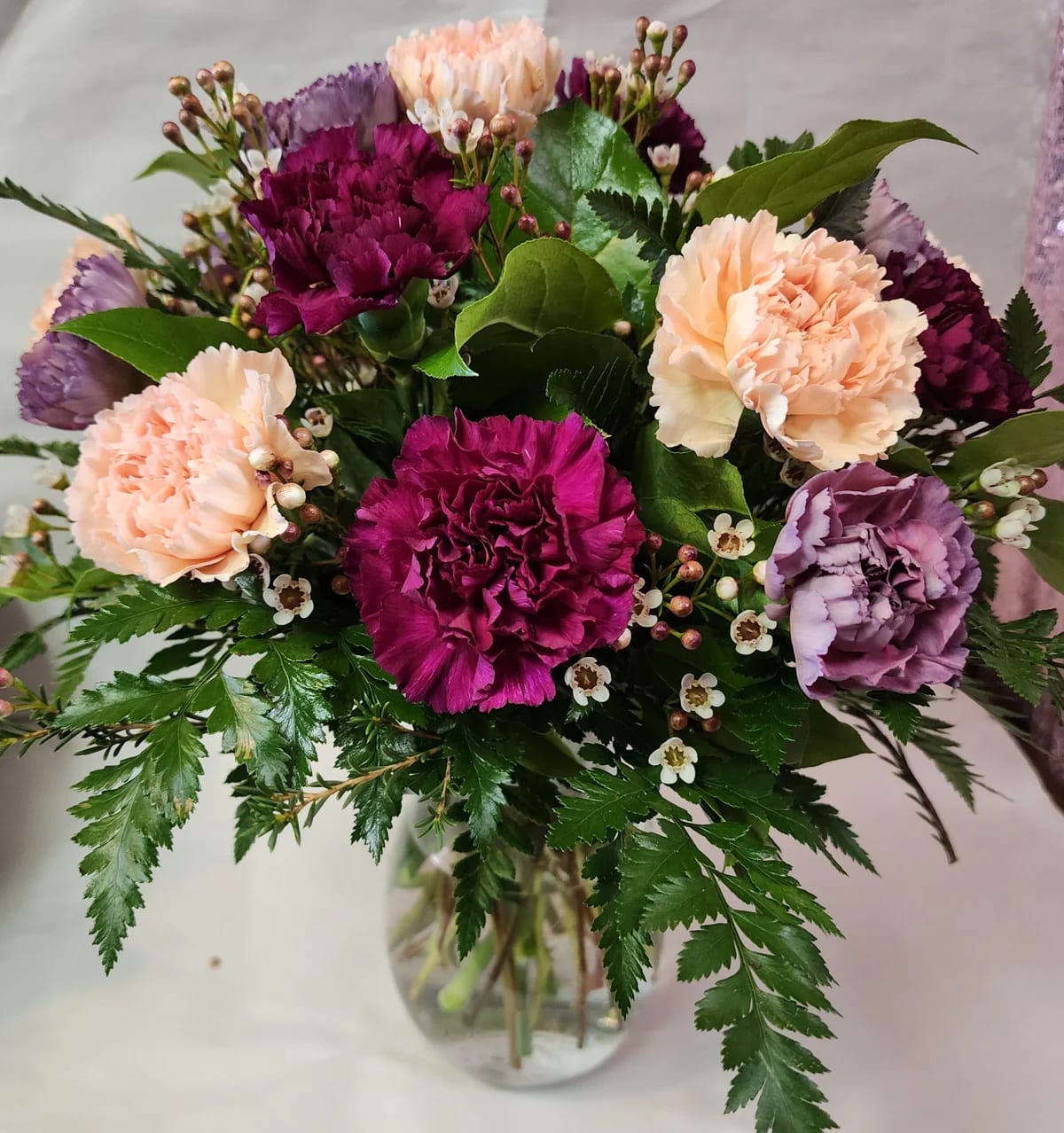 Mixed Carnations - An all around flower arrangement designed with fresh flowers to include mixed colors of carnations, filler, and mixed greens in a vase.   * Some stages of flower life may vary. (Example: Lilies may be more open than imaged.)  Flower shortages and product availability means that some substitutions will apply. Value will always be filled. This bouquet might include eucalyptus amongst the greenery. It may be toxic to pets including but not limited to Cats and Dogs if digested.