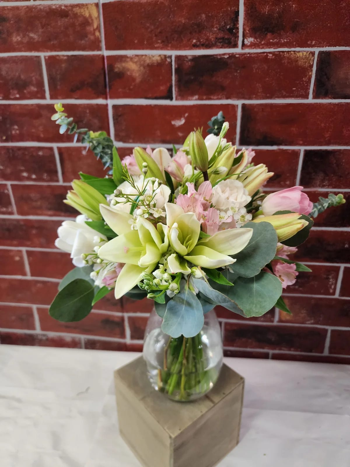 Pastel Pink and White - A custom flower arrangement designed with fresh flowers to include season flowers, mixed greens and a container.  * Some stages of flower life may vary. (Example: Lilies may be more open than imaged.) Flower shortages and product availability means that some substitutions will apply. Value will always be filled. This bouquet might include eucalyptus amongst the greenery. It may be toxic to pets including but not limited to Cats and Dogs if digested.