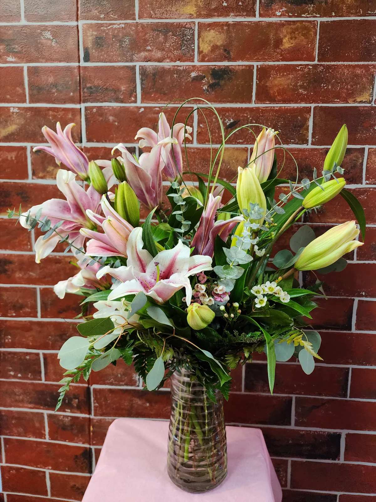 Vase of Lilies - An all around flower arrangement designed with fresh flowers to include lilies, filler, and mixed greens in a vase.   * Some stages of flower life may vary. (Example: Lilies may be more open or closed than imaged.)  Flower shortages and product availability means that some substitutions will apply. Value will always be filled. This bouquet might include eucalyptus amongst the greenery. It may be toxic to pets including but not limited to Cats and Dogs if digested.
