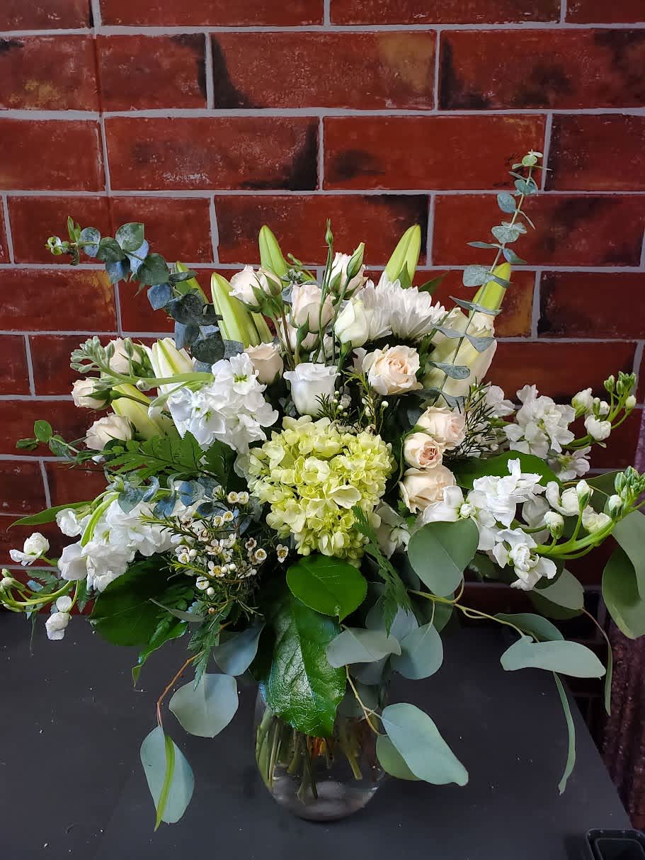 Elevated Beauty - An all around flower arrangement designed with fresh flowers to include white roses, spray roses, green hydrangea, stock, lilies and lots of beautiful greens.  * Some stages of flower life may vary. (Example: Lilies may be more open than imaged.)  Flower shortages and product availability means that some substitutions will apply. Value will always be filled. This bouquet might include eucalyptus amongst the greenery. It may be toxic to pets including but not limited to Cats and Dogs if digested.