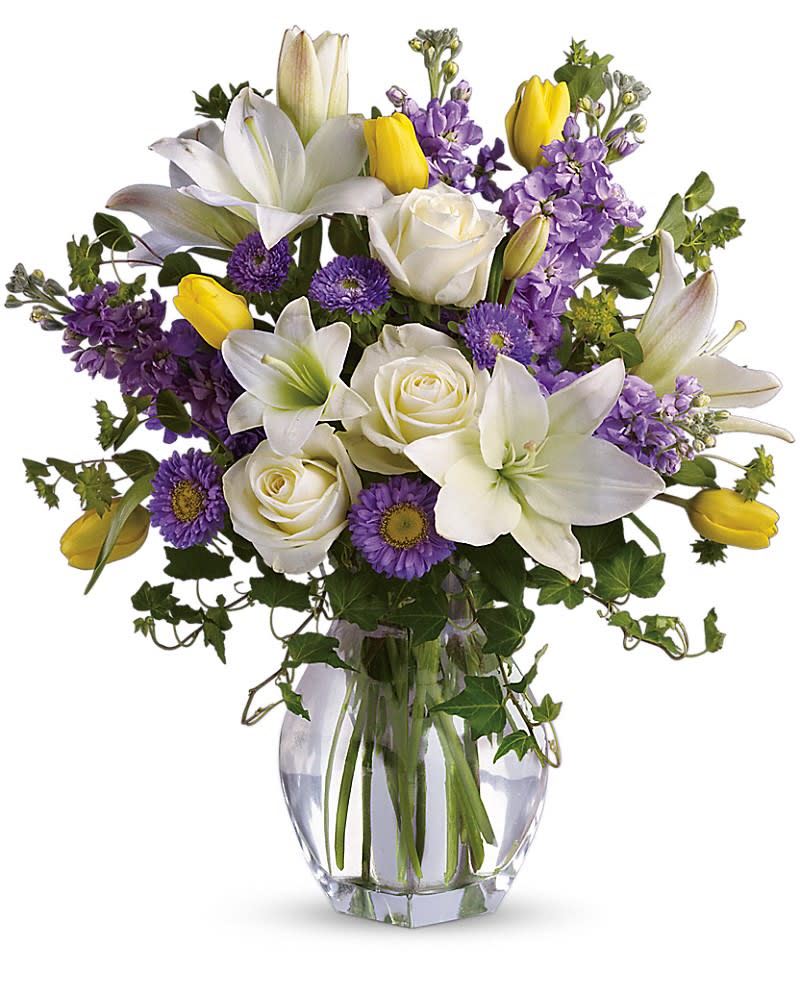 Spring Waltz - Graceful, elegant and timeless, this beautiful spring bouquet offers up colors, blossoms and textures in perfect harmony. Serene crÃ¨me roses, yellow tulips, white asiatic lilies, lavender stock and matsumoto asters are perfectly arranged with spring's freshest greenery and delivered in a lovely clear glass vase. Send it and you'll definitely waltz right in to someone's good graces!
