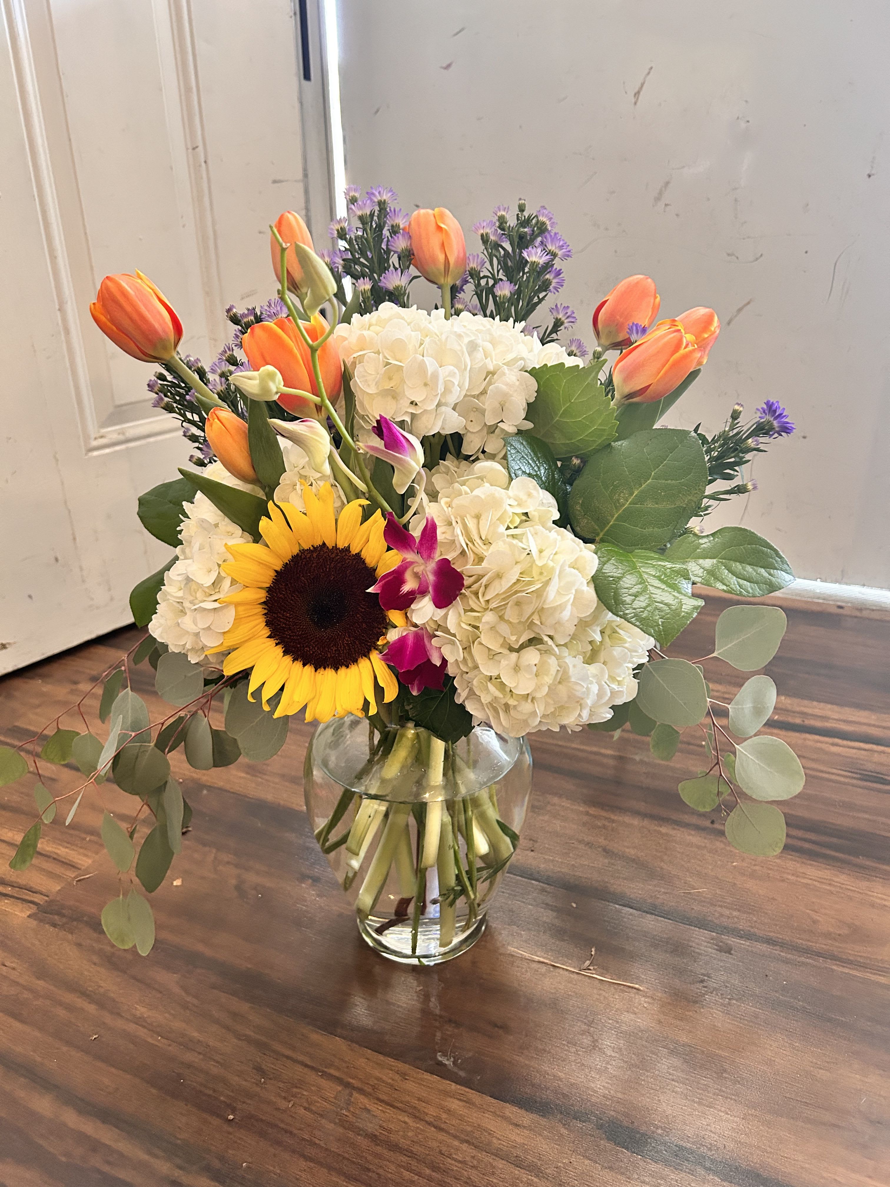 Adored - Adoration, a word used with love and affection with this beautifully designed arrangement by Wonderland Flowers. This arrangement includes roses, hydrangea, sunflowers and beautiful filler flowers with silver dollar eucalyptus . 