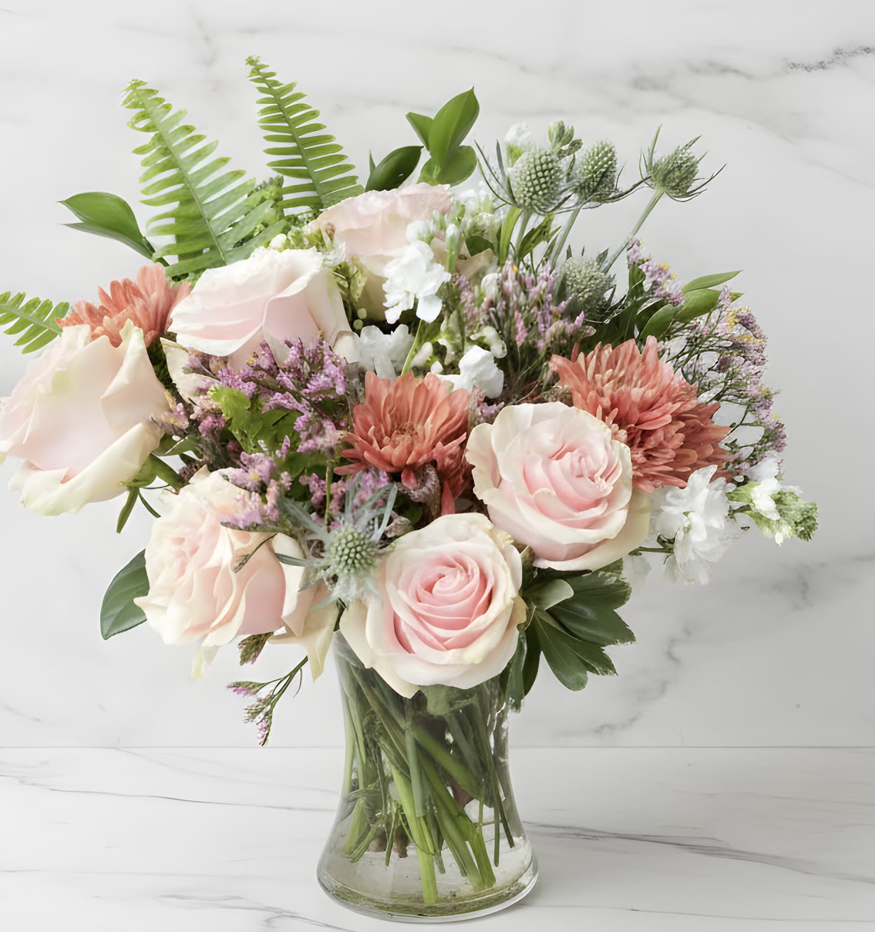 Amour  - Lovely Open Light Pink Garden Roses with Terra Cotta Mums, White Stock, Light Pink Limonlium, and a variety of fun Green Accents.  Ideal for a birthday, anniversary or just because.  Front Facing Bouquet in a 8" glass vase. 