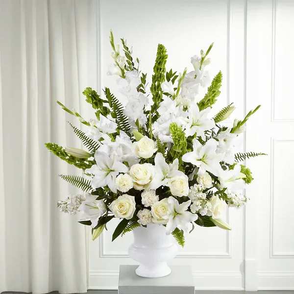 Morning Stars Arrangement - The Morning Stars Arrangment is a brilliant expression of peace and soft serenity. White roses, carnations, gladiolus, stock and Oriental lilies are accented with the bright green stems of Bells of Ireland and a gorgeous assortment of lush greens, while seated in a designer plastic urn to create a beautiful way to honor the life of the deceased.