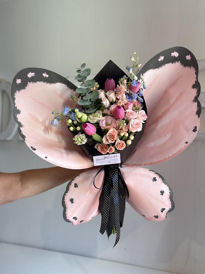 You make my heart flutter - Butterfly handheld wrap, mix arrangement with tulips spray roses and more! Handheld bouquet , you may request certain color wrap, no vase included. Call to request vase if needed.