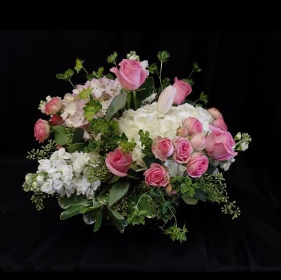 Queen of Hearts - “Queen of Hearts” is a delicate, feminine arrangement showcasing soft pink roses, spray roses, and hydrangeas accented with wispy greenery. Overflowing with charm and elegance, this bouquet captures the essence of grace and heartfelt beauty.  
