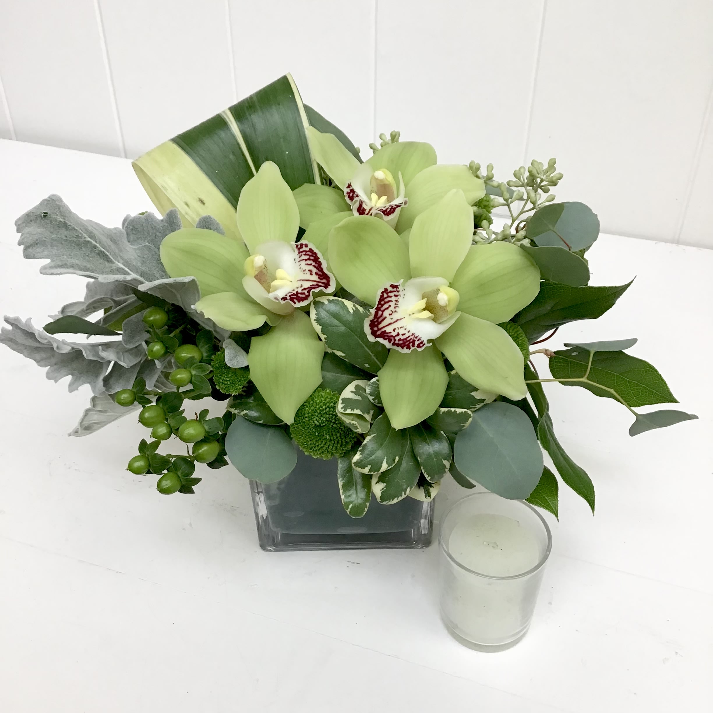 Kiss - This petite glass cube gently holds cymbidium or dendrobium orchids, dusty miller, and hypericum berries. Perfect to let someone know you are thinking about them.