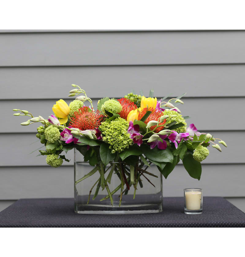 Pin Up - This modern vase is anything but ordinary. Arranged with protea, hydrangeas, and dendrobium orchids.