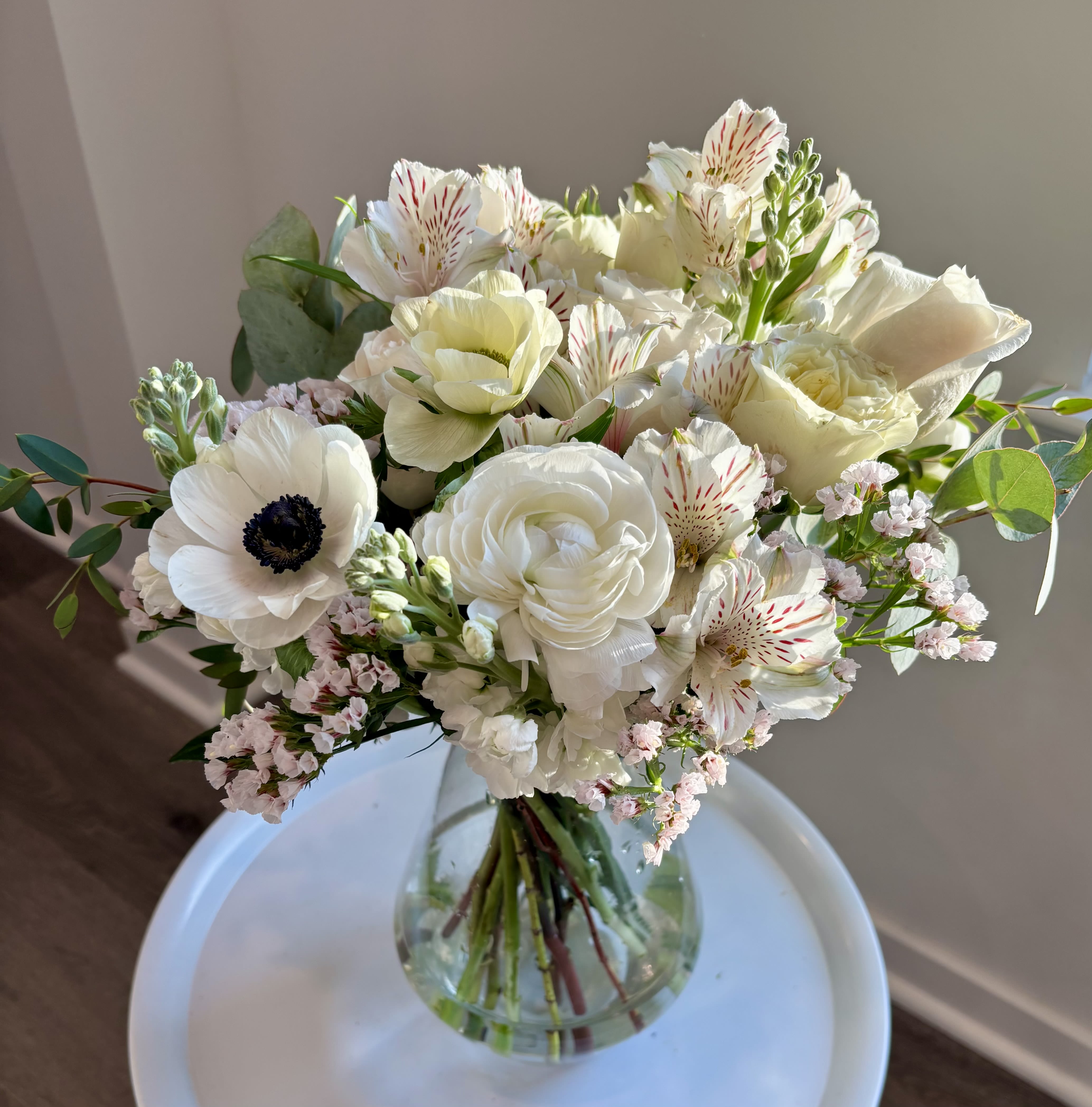 Linen &amp; Light - A fresh, airy arrangement featuring layered white blooms, soft texture, and natural greenery. Designed with a thoughtful mix of seasonal florals, this piece highlights movement, balance, and simplicity. Perfect for brightening everyday spaces, gifting, or adding a calm, elevated touch to any room. Designer’s choice using the freshest blooms available