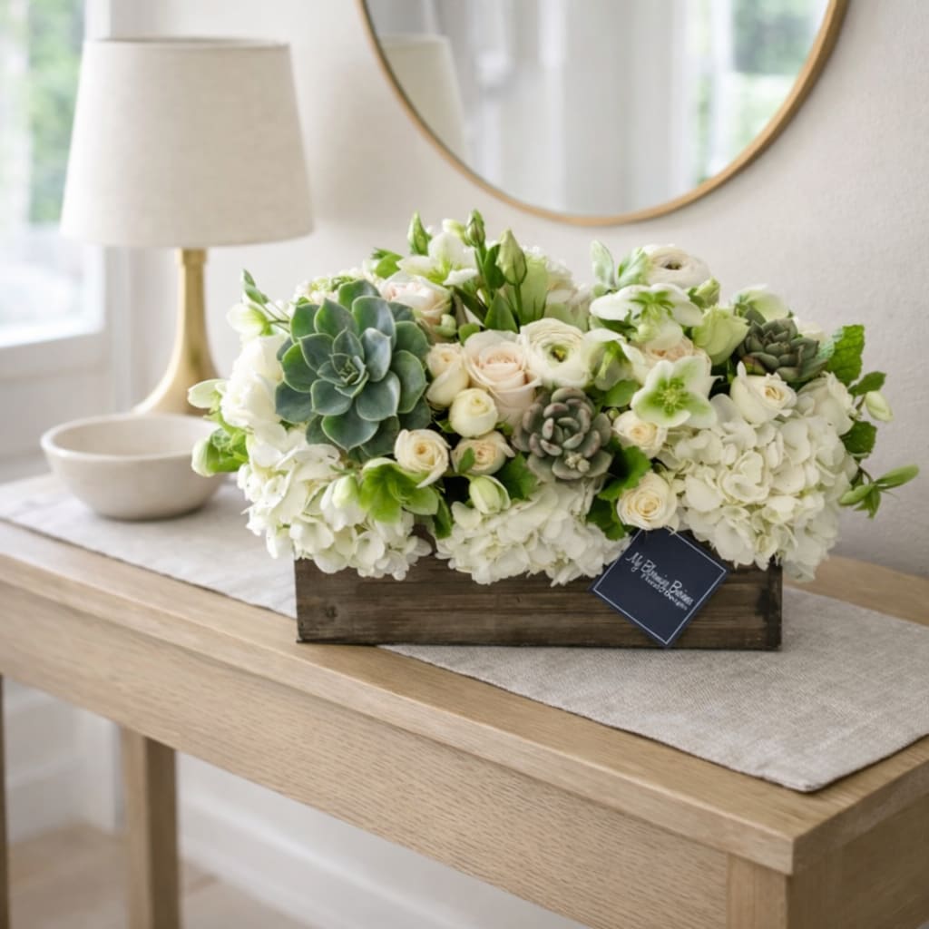 The Mulholland  - The Mulholland is your perfect blend of rustic and elegance! This beautiful and unique box arrangement flaunts white flowers, lisianthus, spray roses, and other seasonal florals, with some succulents to tie it all together. Named after the Winding Roads of Mulholland Drive, this arrangement offers a touch of glamour and evening sky vibes. Perfect for your friends or family, this arrangement brings sophisticated and intriguing floral vibes to any room. Give your loved ones something truly special with the Mulholland!