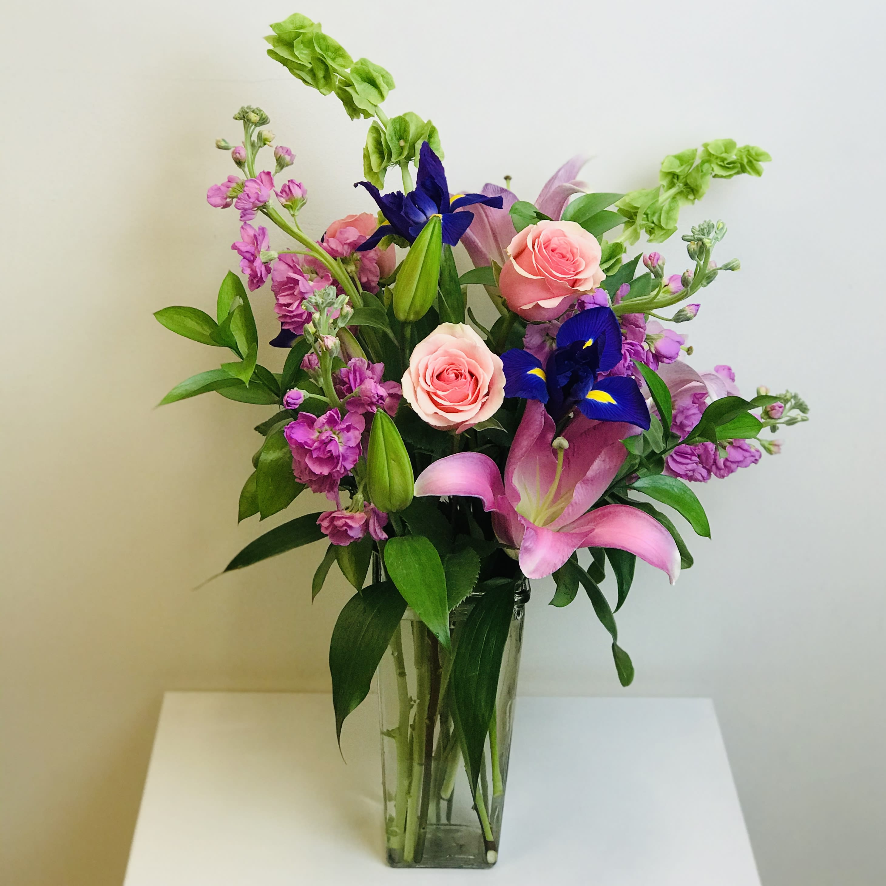 Enchanted Fairytale  - This arrangement contains an enchanted mix of lilies, bells of ireland, stock, iris, roses, and other beautiful blooms. Lilies may arrive in bud form when ordering closer to delivery date, but will open beautifully in 3-4 days.  Container Country of Origin: China Flower Country of Origin: Ecuador and/or Columbia