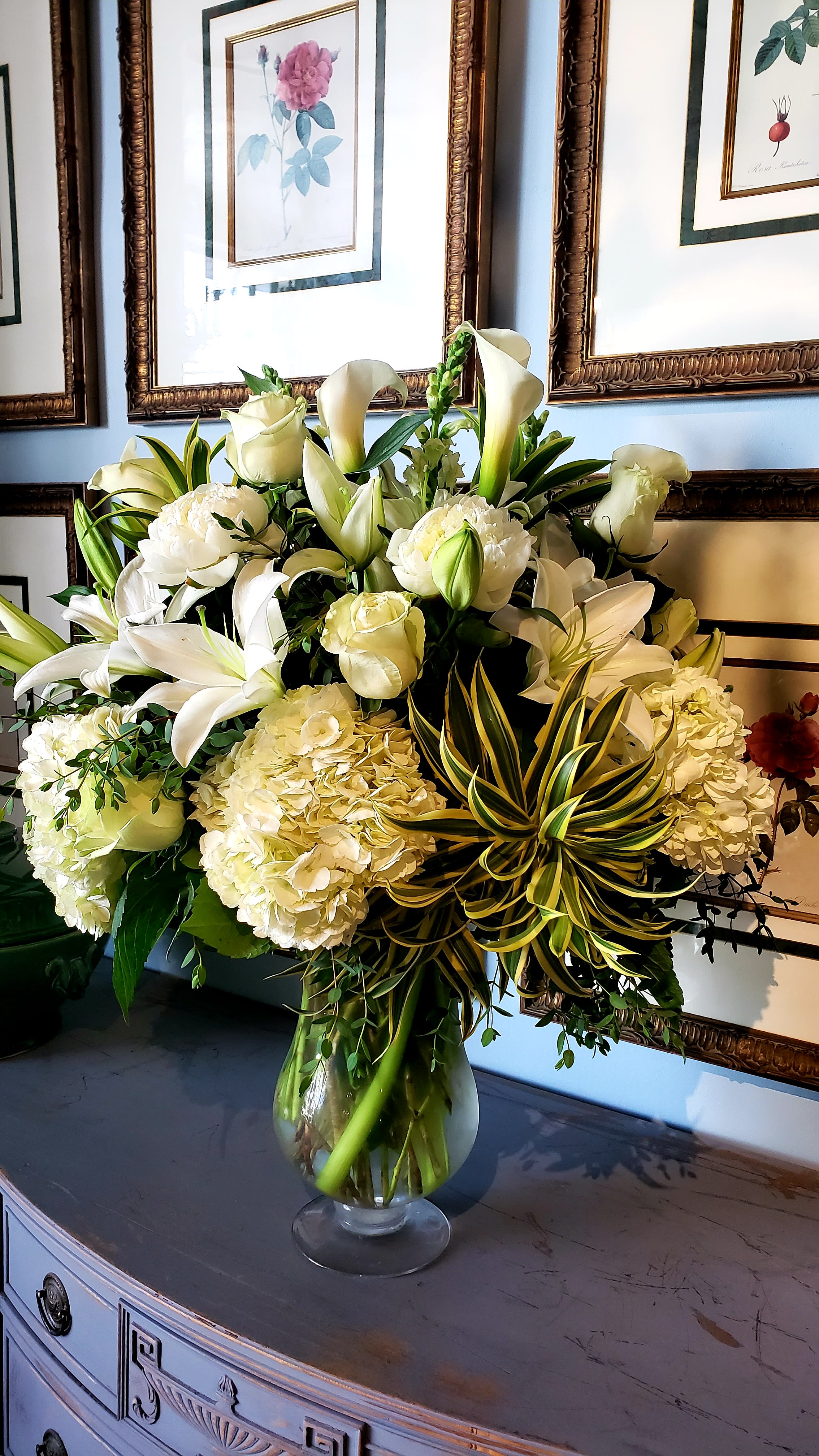 Luxe in White  - Elegance and purity come together in this breathtaking arrangement, featuring a large glass vase filled with luxurious white seasonal flowers. With high-end blooms such as hydrangeas, roses, stock, and lilies, complemented by lush greenery, this arrangement exudes sophistication and timeless beauty. Perfect for weddings, upscale events, or simply making a bold statement in any space, this all-white masterpiece will never go unnoticed.  Please note: Floral variety and vase may vary depending on availability, ensuring each arrangement is fresh and unique.  Freshness Guarantee: At Belden's Florist, we stand behind the quality of every arrangement. Our flowers are guaranteed to remain fresh and beautiful for 3–5 days after delivery. While cut flowers may naturally begin to wilt beyond this timeframe, we ensure that only the freshest blooms are selected and expertly arranged to bring joy and elegance to your space. To extend their life, we recommend refreshing the water in your vase daily, allowing your flowers to stay hydrated and continue to dazzle.