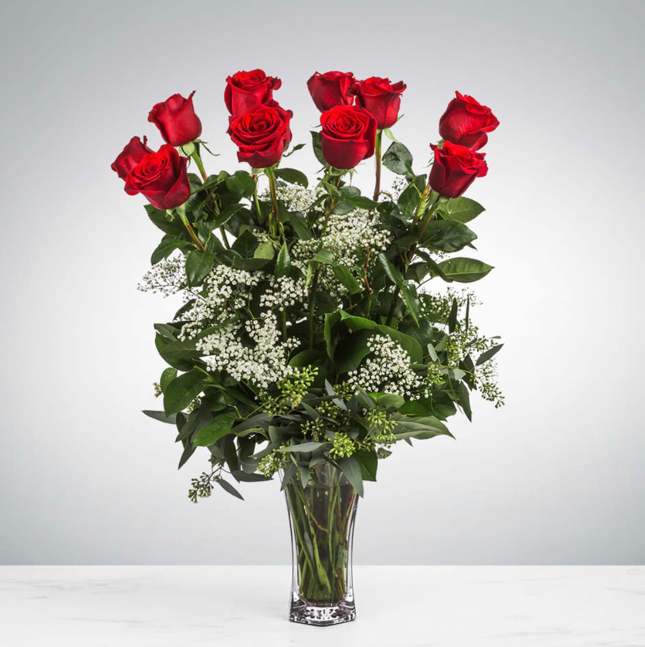 Dozen Long Stemmed Red Roses with Baby's Breath  - One dozen long stem red roses with baby's breath accented with premium greeneries in a clear glass vase.   APPROXIMATE DIMENSIONS: 25" H X 18" W
