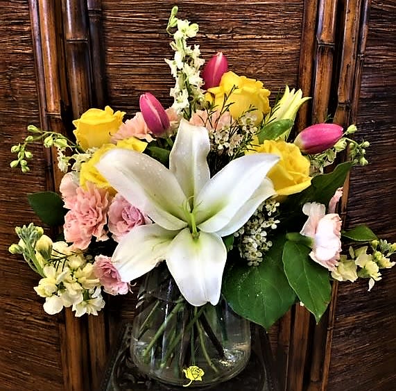 A Touch of Love - A gorgeous arrangement designed in a clear glass vase with our beautiful large Casablanca lilies, Yellow roses, Pink tulips and other beautiful blooms.
