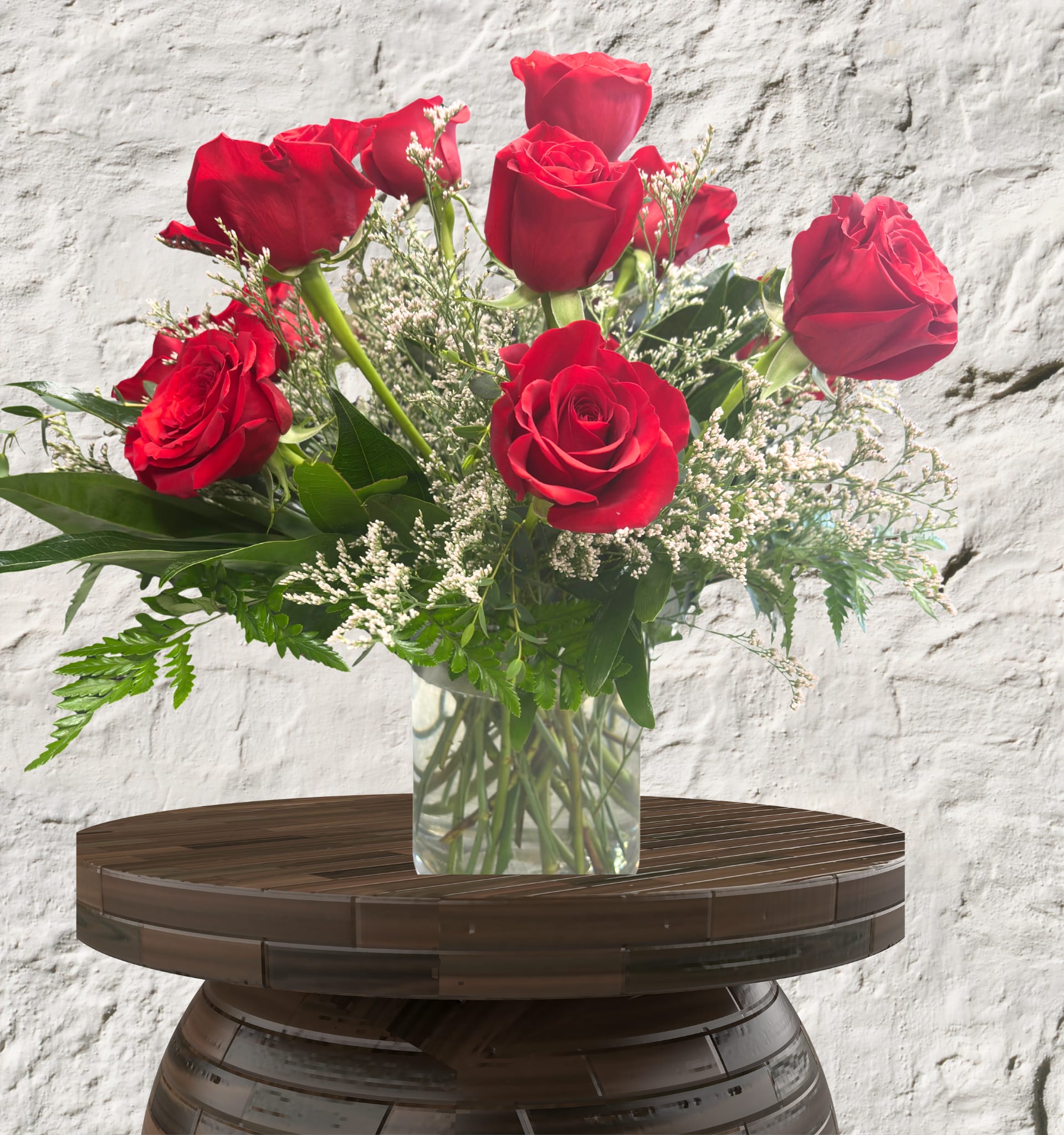Crimson Muse - Timeless Sophistication. Pure Romance. Iconic Beauty.  The Classic Dozen is our definitive tribute to the most celebrated flower in history. This arrangement is designed for those who appreciate the power of tradition and the elegance of a singular, perfect bloom. By focusing on a monochromatic palette of rich, deep red, we highlight the exquisite velvet texture and architectural spiraling of our premium-grade roses.  The Design &amp; Florals This collection is a masterclass in clean, high-end floral styling, allowing the quality of each stem to speak for itself.  Premium Blooms: We utilize 12 designer-grade red roses, chosen for their exceptional head size, sturdy stems, and deep, consistent color.  Artful Accompaniment: To enhance the vibrant red without distracting from it, the arrangement is accented with delicate white fillers and lush, leathery greenery.  The Upscale Vessel: Set in a heavy-weighted, clear glass cylinder. This minimalist foundation offers a contemporary edge to the classic rose, ensuring the focus remains entirely on the stunning floral display.  The Perfect Gesture The Classic 12 is a refined and elegant standard. Featuring 12 premium roses, this arrangement is a timeless choice for a bedside table, a sophisticated desk, or a thoughtful "just because" luxury gift.