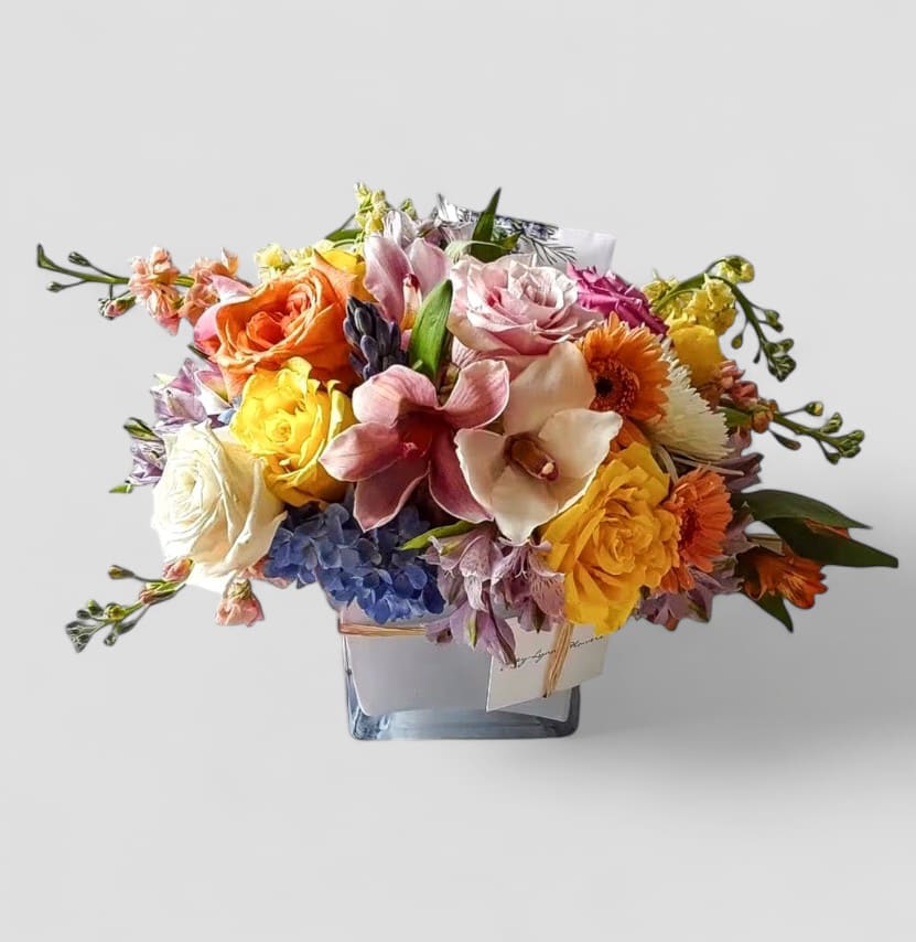 Mixed Blossom Beauty Designer's Choice - Beautiful mixed blossoms of that day roses orchids and more arranged in a modern white glass vase. Perfect to send today for every occasion to show them how much you care. Always made unique and extra special. Please visit my beautiful gallery to see my latest designs that I have created for my online customers. Send them happiness today.