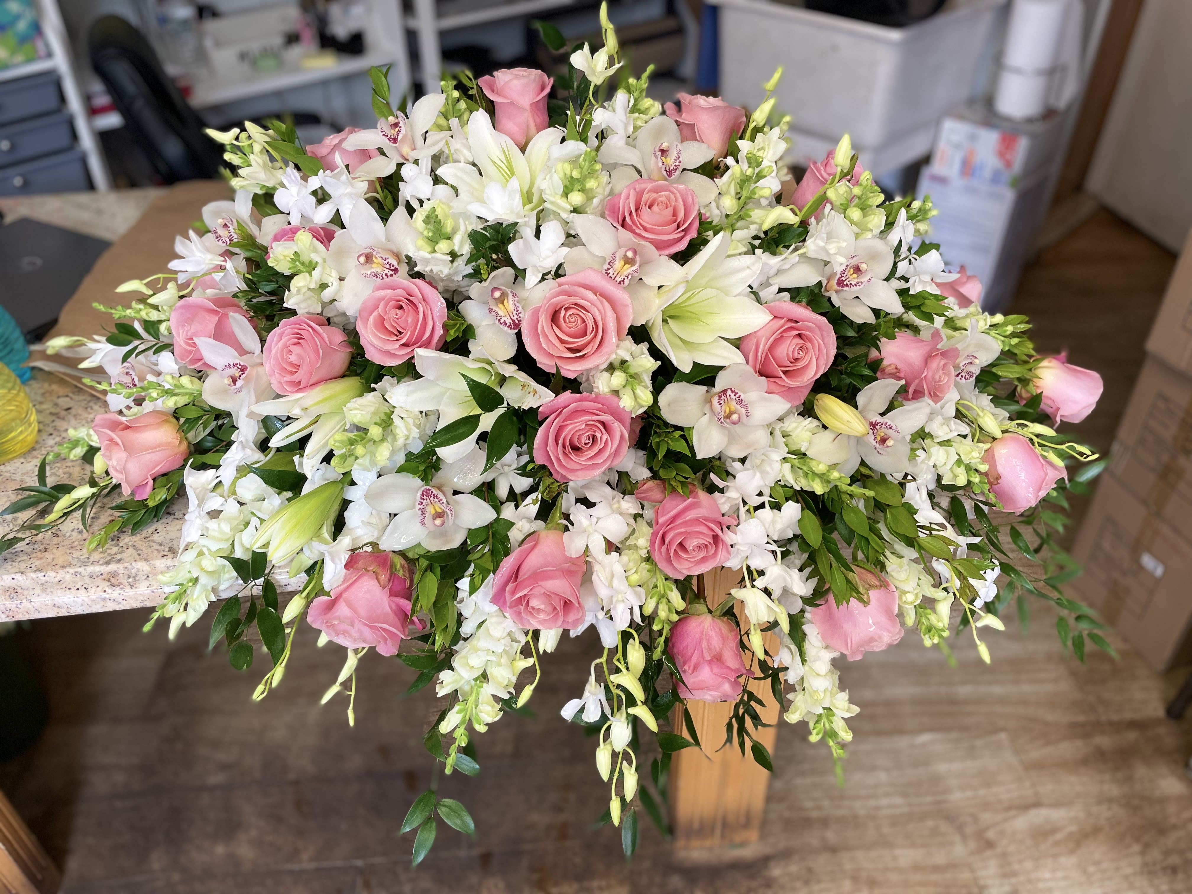 Remembering in Grace Casket Spray - Foliage includes: Lily, Rose, Cymbidium Orchid, Dendrobium Orchid, Snapdragon with greeneries.  We advise our customers to order 24-48 hours in advance of their scheduled delivery to ensure that we are able to have similar flowers and colors in the shop for their order.  $600 (standard) as shown 