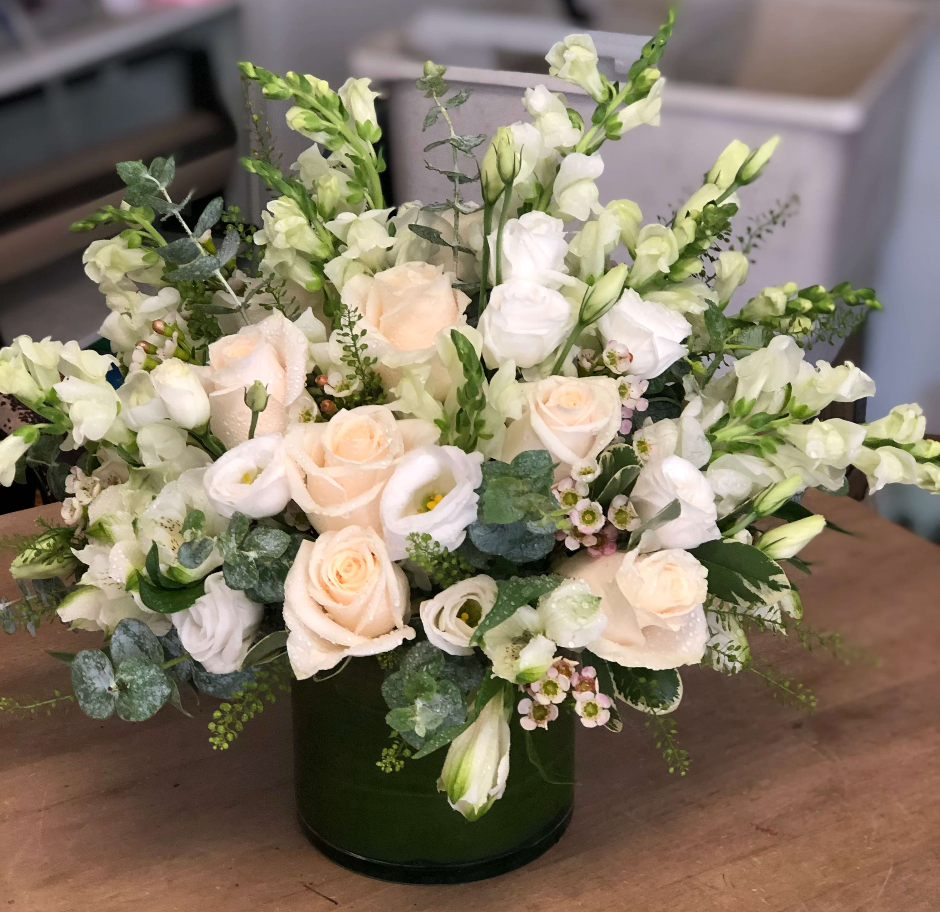Rustic White - A mixed ivory and white tones, filled with rose, lisianthus, snapdragon, alstroemeria, wax flower, and baby blue eucalyptus.   Because we like to use unique and different blooms every week, we advise our customers to order 24-48 hours in advance of their scheduled delivery to ensure that we are able to have similar flowers and colors in the shop for their order.  $90 (standard) as shown