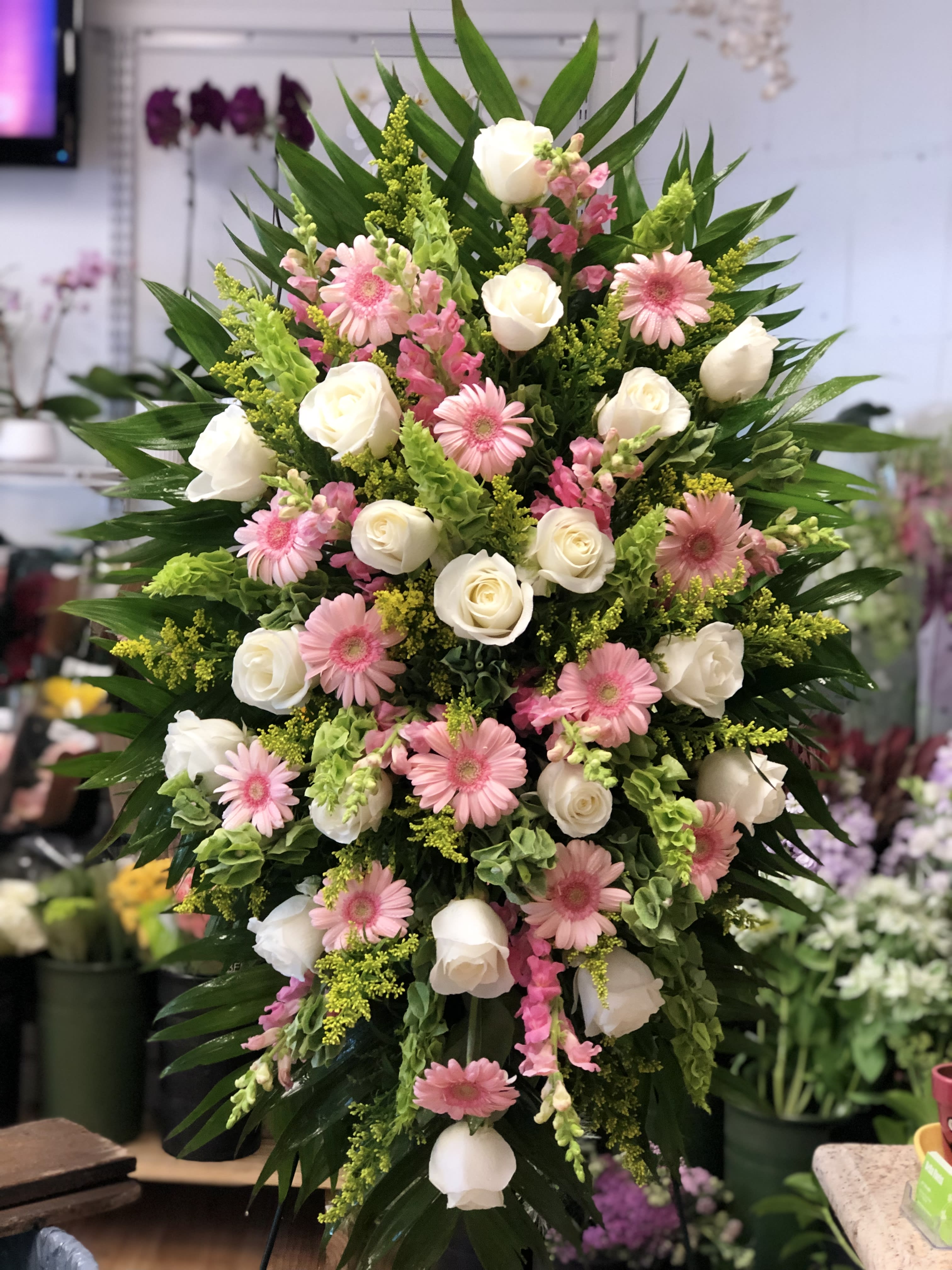 Standing Spray 11 - Foliage includes: Rose, Snapdragon, Solidago, Gerbera Daisy and Bells of Ireland.  We advise our customers to order 24-48 hours in advance of their scheduled delivery to ensure that we are able to have similar flowers and colors in the shop for their order.  $200 (deluxe) as shown