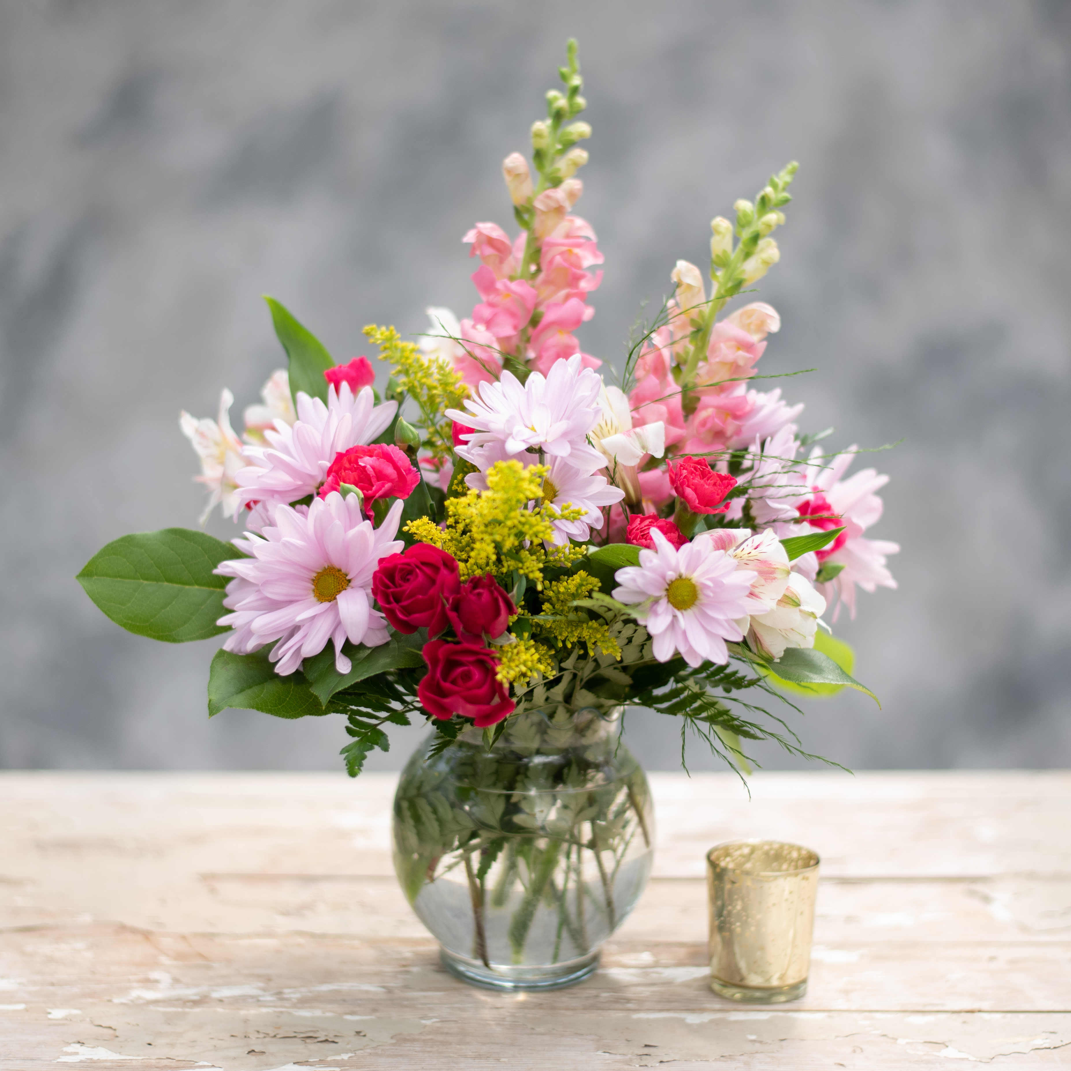Free Spirit - This petite arrangement is in a glass ivy bowl and is overflowing with lavender daisies, alstroemeria, pink spray roses and snapdragons, with highlights of yellow solidago.  A perfect accent for a bedroom nightstand. 
