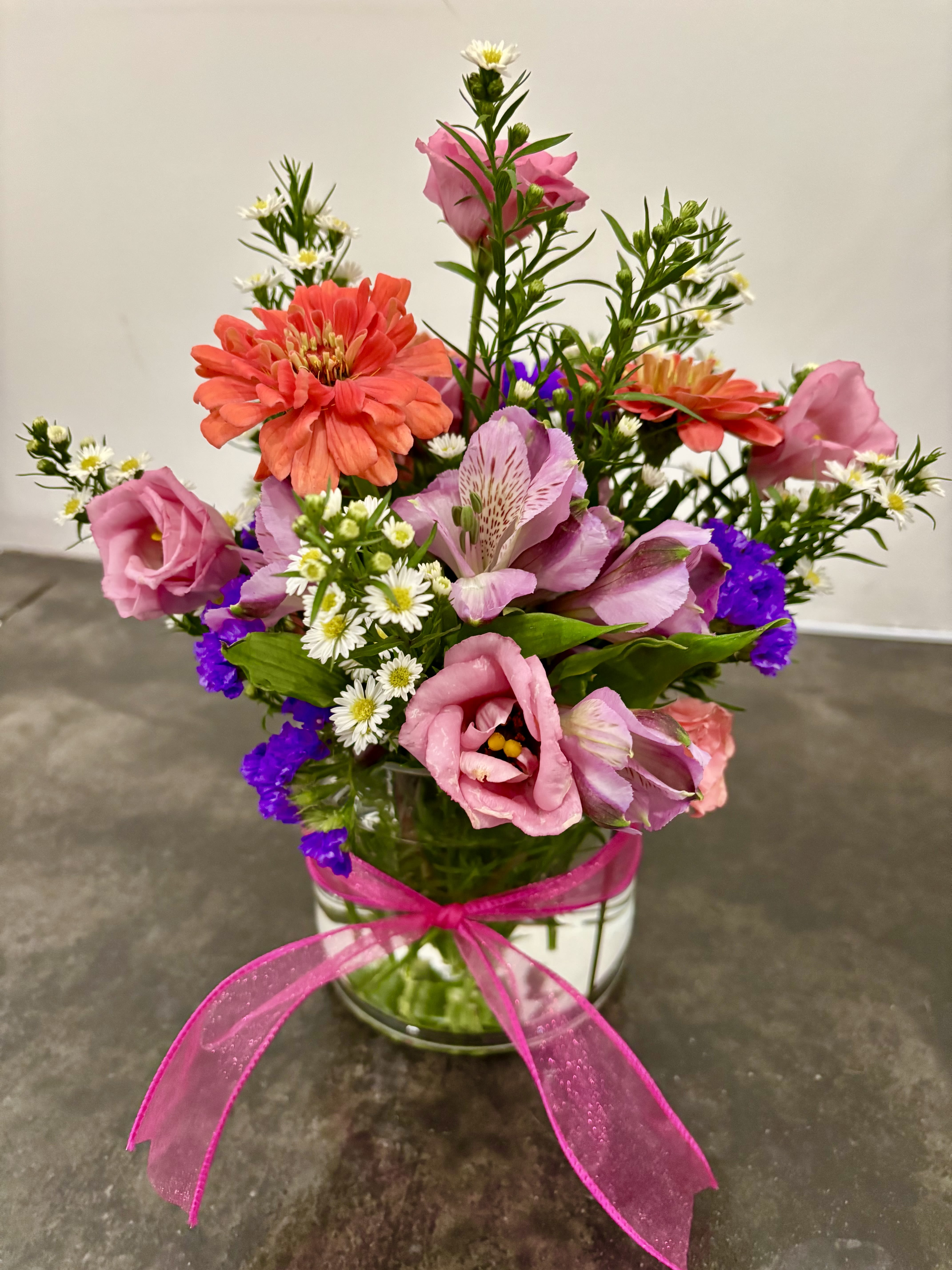 Color me happy - Brighten someone's day with this sweet mix of garden-fresh, blooms! Featuring cheerful pinks, purples, coral and white, this arrangement is designed in a clear 5" round glass vase with a pretty pink ribbon (flowers and colors are subject to change due to availability). This one is perfect for birthdays, thank you's, thinking of you or just because!