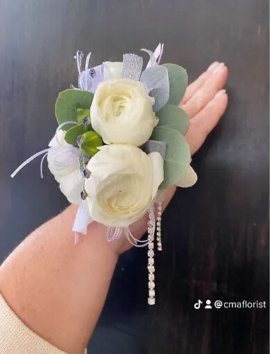 Elegant Wristlet - This wrist corsage features white ranunculus, eucalyptus leaves, rhinestones and colored stones.
