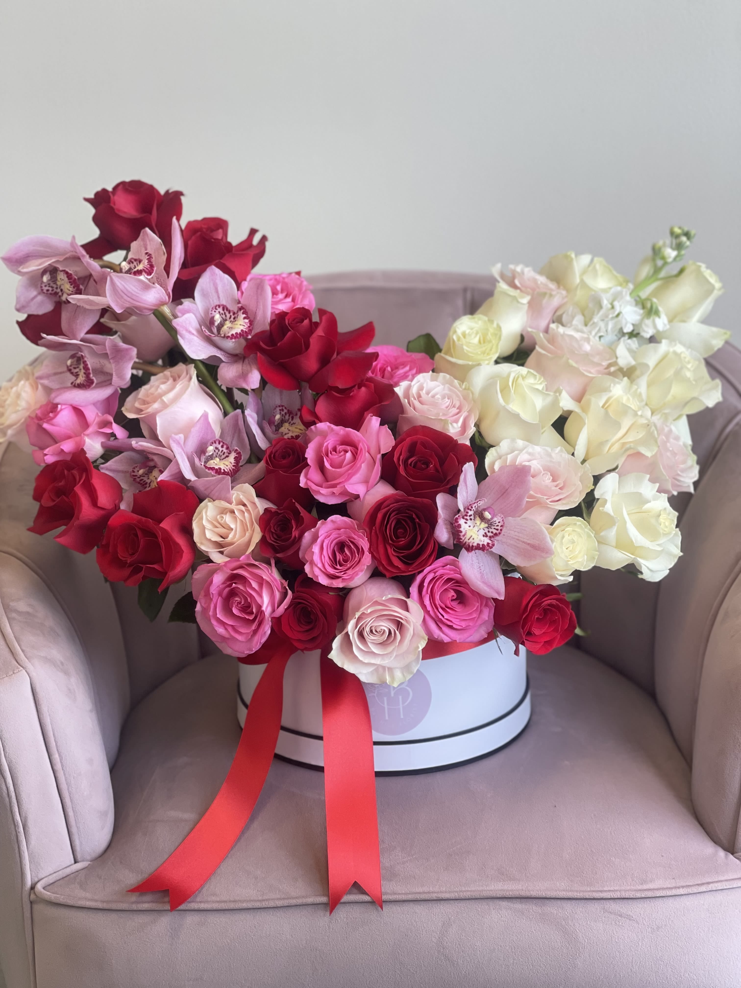 Blush and Bloom  - A breathtaking ombré rose and orchid arrangement that seamlessly transitions from soft blush to deep crimson, embodying the essence of romance! This arrangement is a stunning visual representation of love’s beautiful evolution-perfect for Valentine’s Day.