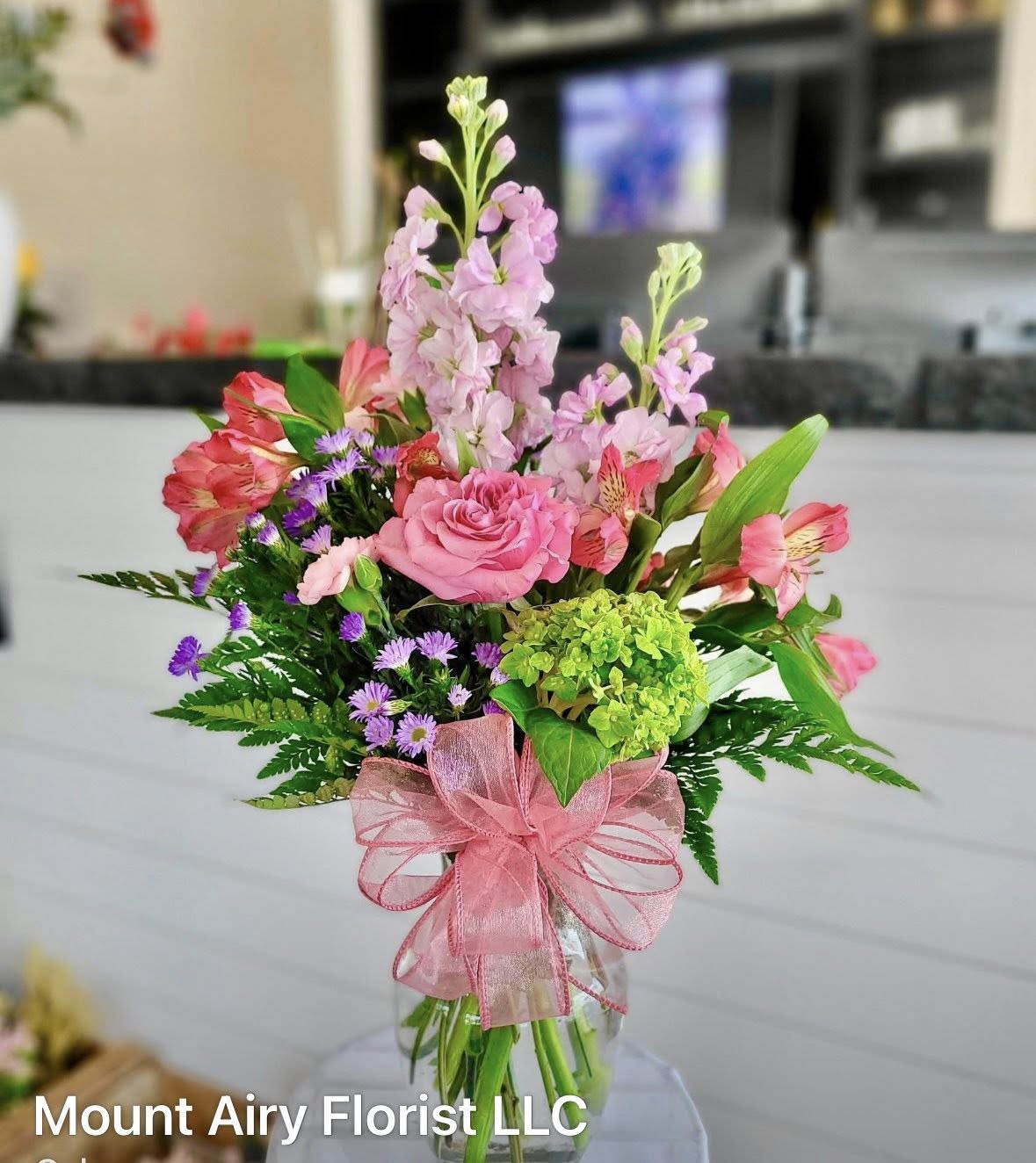Timeless Beauty - A beautifully designed mixed floral arrangement featuring a romantic blend of pinks, purples, and greens. This timeless beauty is arranged in a glass vase by our talented floral team and is perfect for expressing, love, appreciation and heartfelt sentiment.
