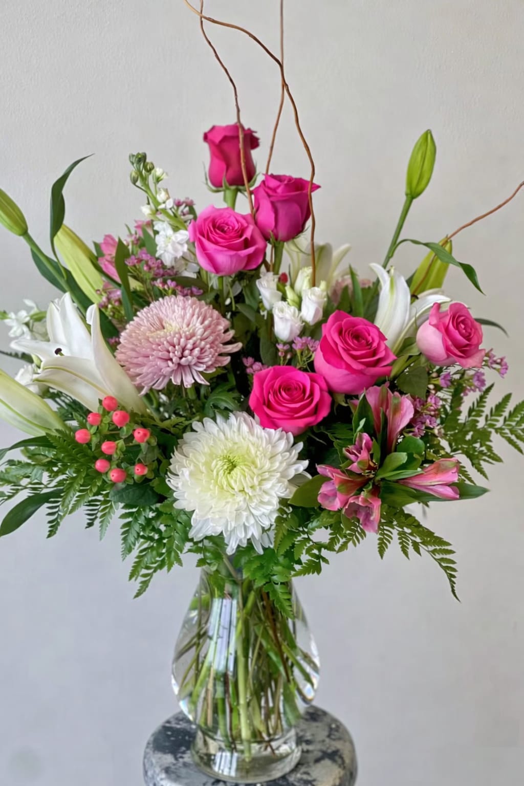 Cupids Love  - A pink, red, and white Valentine's Day floral arrangement typically features a beautiful mix of roses, peonies, and lilies. The soft, romantic pinks evoke love and affection, while the deep reds symbolize passion and desire. White flowers, like lilies or daisies, add purity and elegance to the bouquet. Greenery and delicate filler flowers, like baby’s breath, are often included to enhance the arrangement and give it a fresh, full look. The combination of these colors creates a balanced, stunning display perfect for celebrating love and affection on Valentine’s Day. It’s a timeless and classic choice for expressing deep emotions.