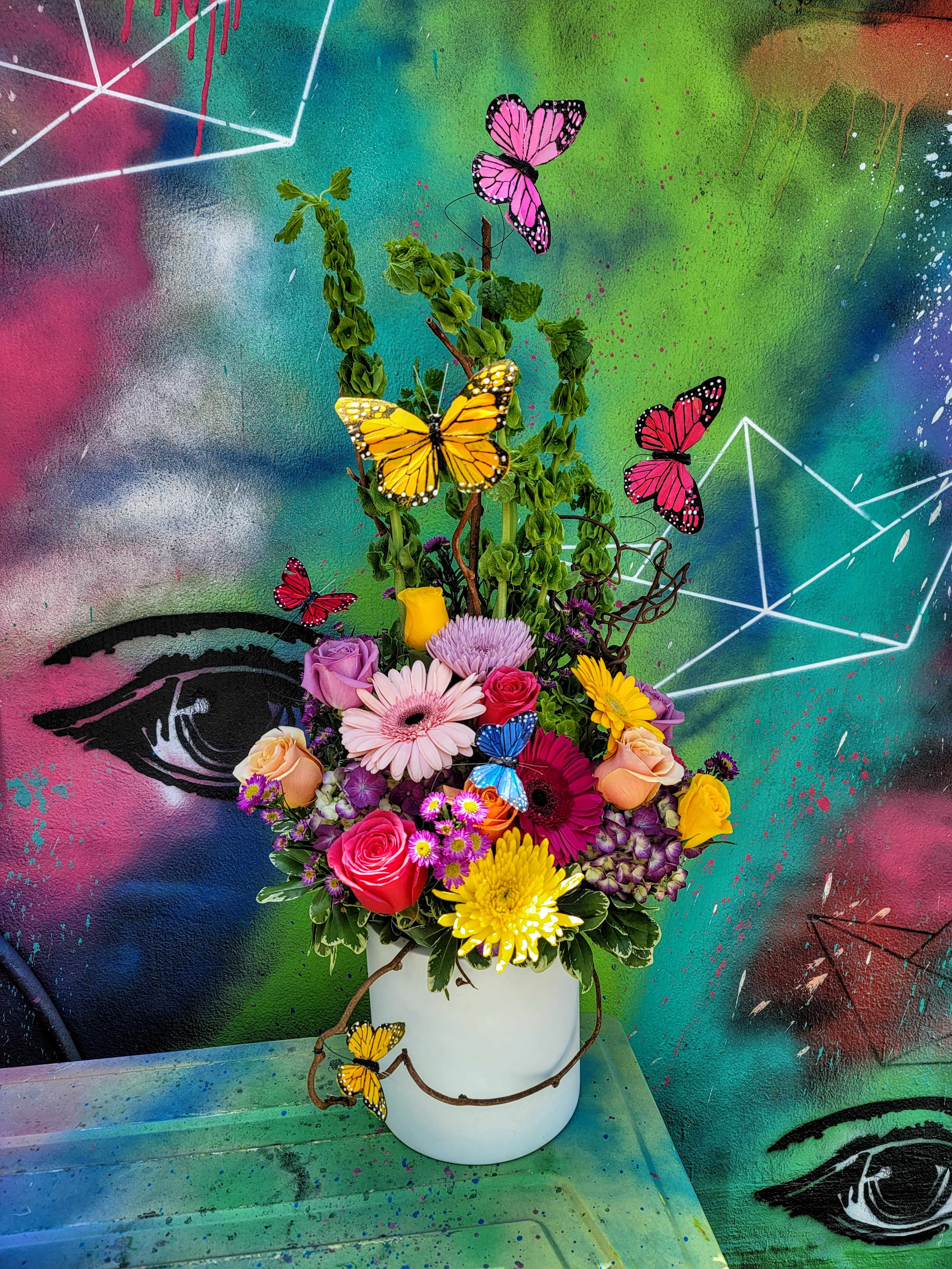 technicolor butterfly - An arrangement made with roses, hydrangeas, mix flowers and greenery in a cylinder vase