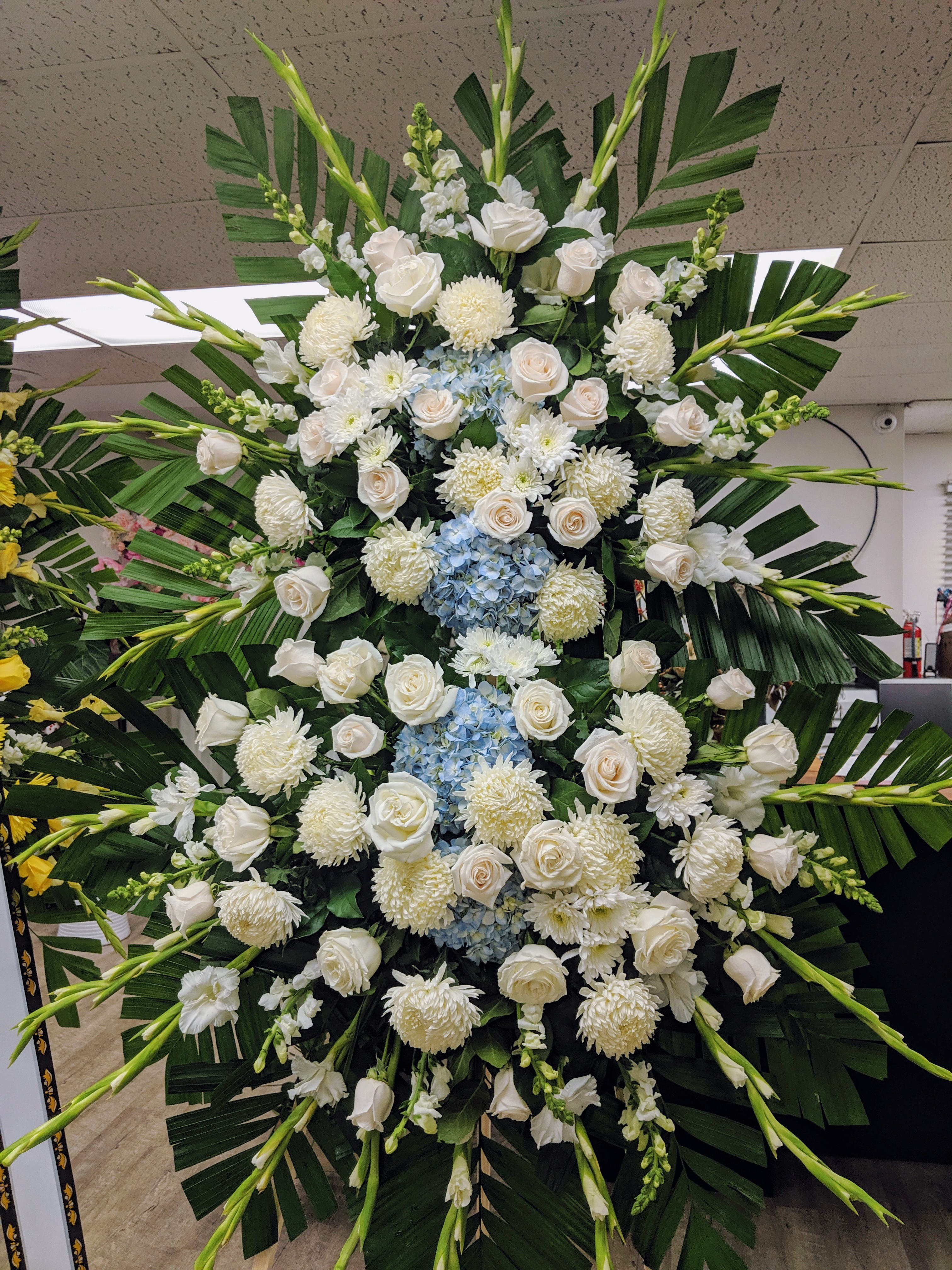 Pure Tranquility Standing Spray - A standing spray with all whites with blue Hydrangea accents. Option to add banner- please note under SPECIAL INSTRUCTIONS. 