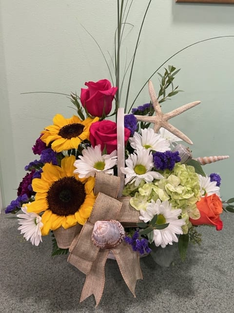 Country Shores (CSB) - That country look with a touch of the shore!  Sunflowers, roses, daisies, hydrangea with the added touch of shells and starfish make up beautiful design. approximately  14in X 15in *Basket may differ. *Flower color may differ.  *Bow may differ Same look and feel