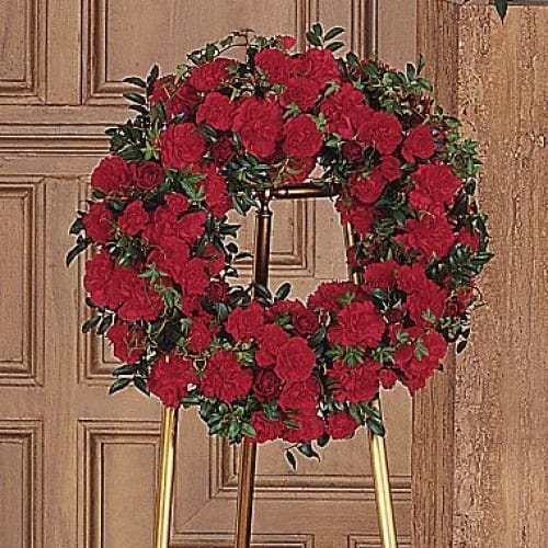 Carnation Wreath - This circle of life features a blossoming array of red spray roses and carnations, in honor and remembrance of a loved one. 