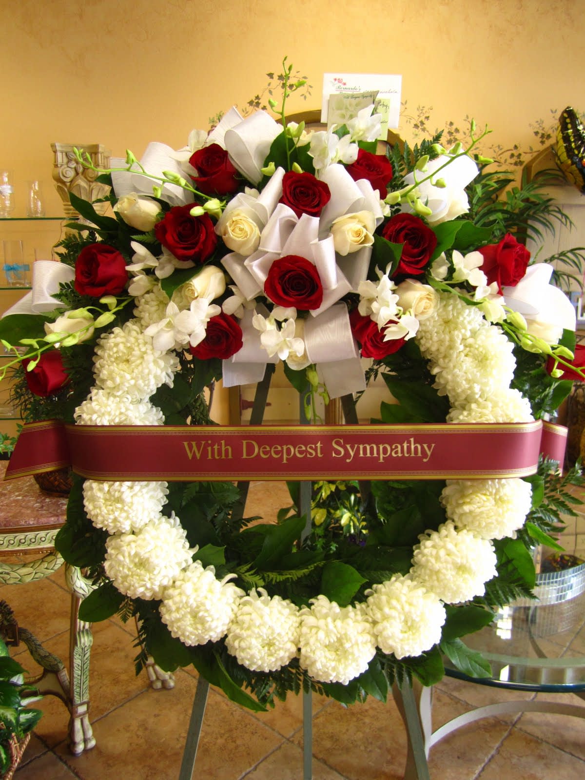 BFS-W4 Wreath - Introducing our Sympathy Wreath: A Striking Memorial Tribute with Premium Red and White Roses, Dendrobium Orchids, and White Mums, Embellished with a "With Deepest Sympathy" Banner – Measuring 26 Inches in Diameter, a Grand Symbol of Comfort and Remembrance.