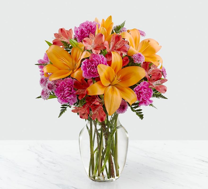 Light of My Life™ Bouquet- VASE INCLUDED - The Light of My Life™ Bouquet blossoms with brilliant color and a sweet sophistication to create the perfect impression! Orange Asiatic Lilies make the eyes dance across the unique design of this flower bouquet, surrounded by the blushing colors of red alstroemeria, lavender button poms, fuchsia carnations, and lush greens. Presented in a clear glass vase, this fresh flower arrangement has been created just for you to help you send your sweetest thank you, happy anniversary, or thinking of you wishes. 
