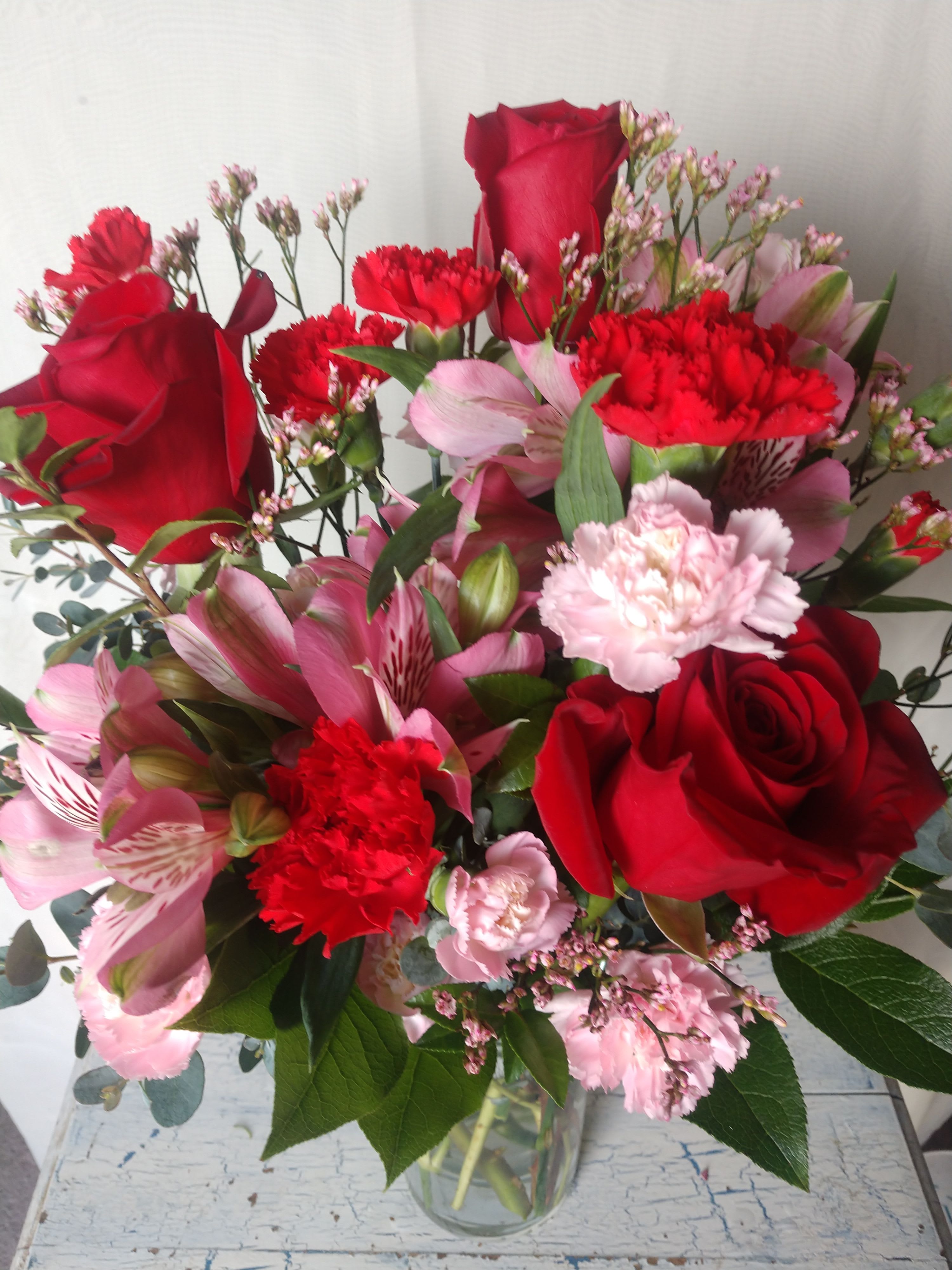 Designers Choice Romantic Mix Deluxe - A beautiful and fresh mix of red and pink premium flowers arranged in a glass vase.