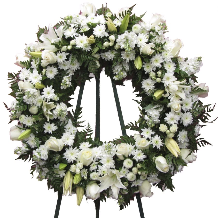 Purity Tribute Wreath - A white beauty like our "Purity Tribute Wreath" expresses pure sympathy and compassion towards a family's loss. Our wreath is made with fresh roses, siberia lilies, button pom poms, and spray roses, supported by a free-standing easel. 