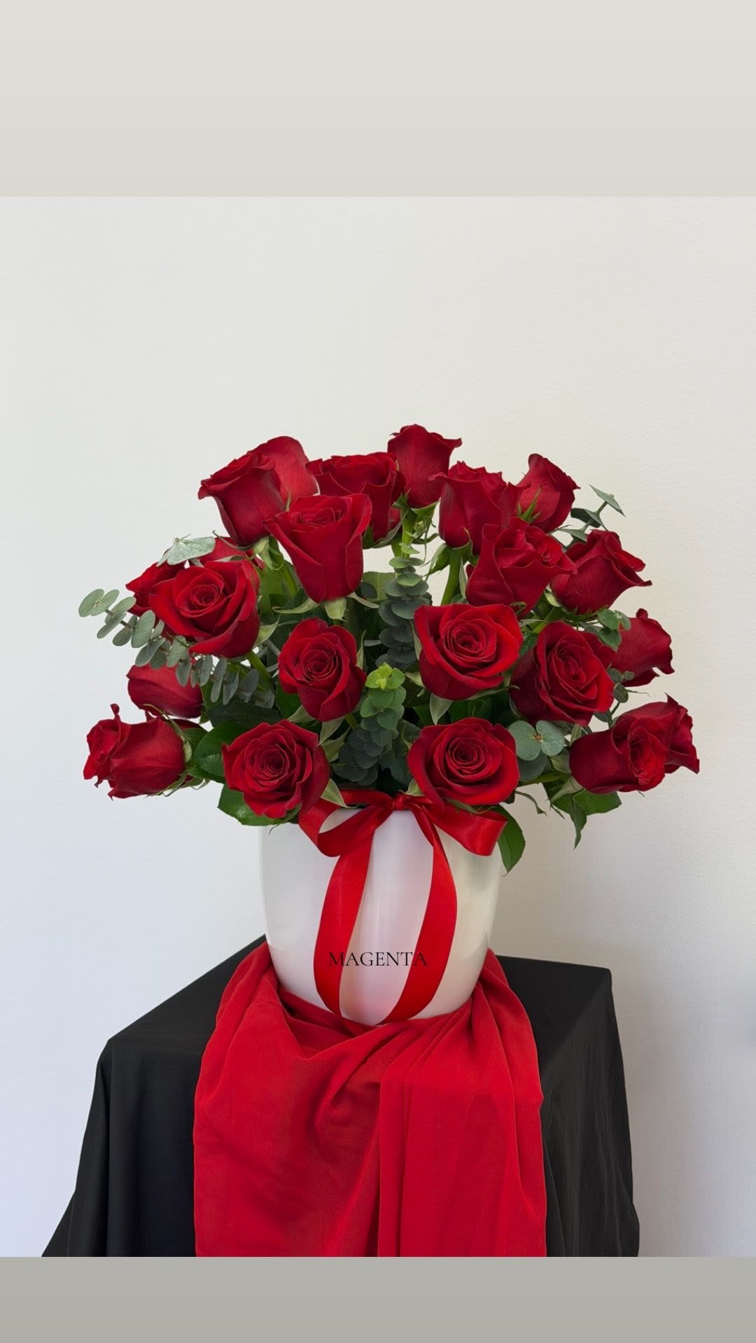 25 Red Roses in White Ceramic Vase - Celebrate love this Valentine’s Day with a luxurious arrangement of 25 premium red roses accented with fresh eucalyptus, beautifully designed in a sleek white ceramic vase. A timeless and romantic gift that speaks straight from the heart. 