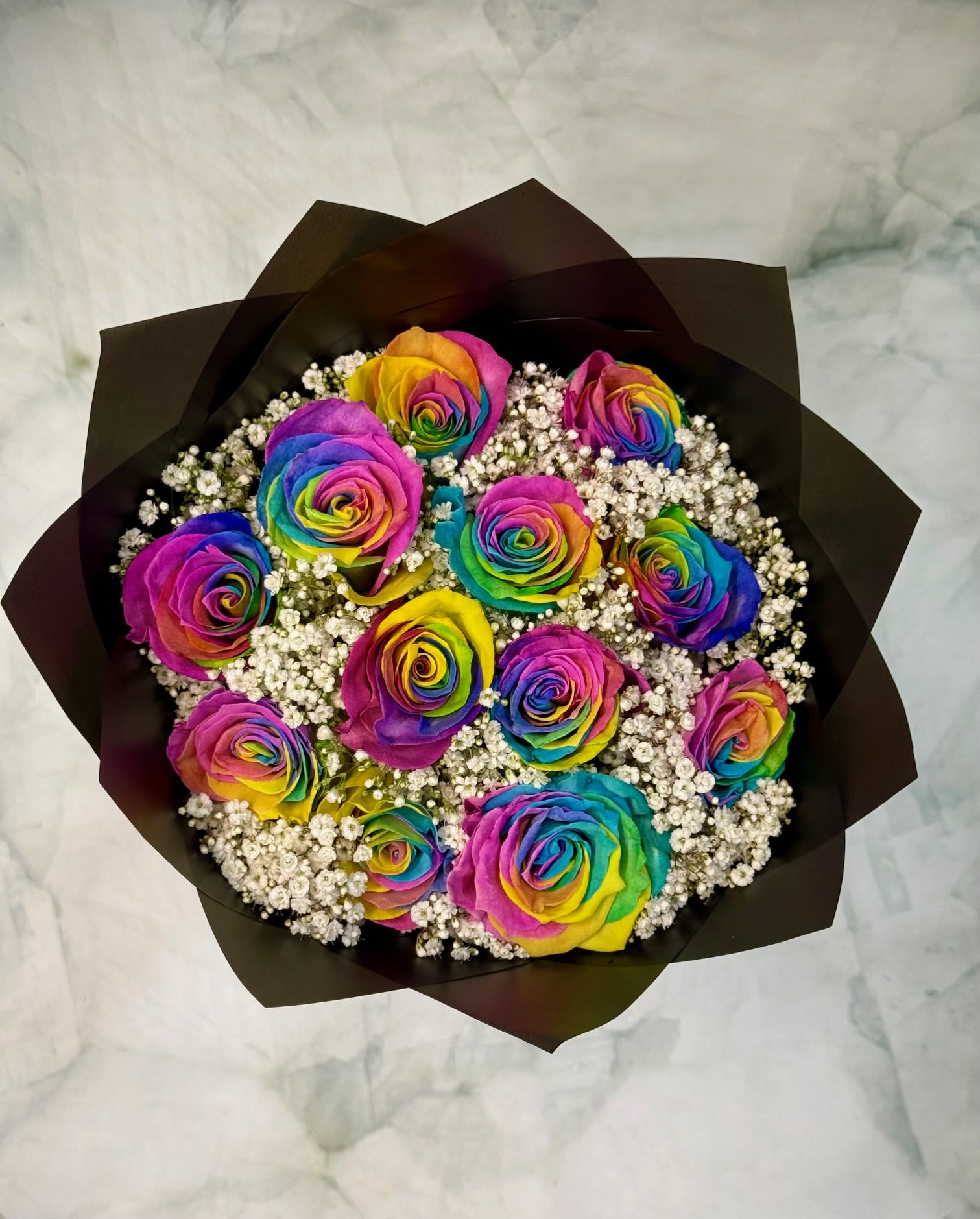 Radiant Rainbow Rose Bouquet - These are 12 of our one of a kind rainbow roses that are arranged in a round bouquet and wrapped with black premium waterproof paper. This is a show stopper bouquet that will blow them away.