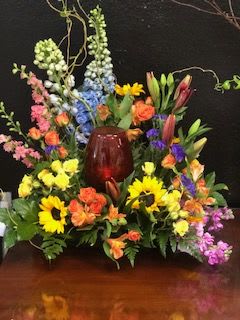 Forever Lasting Love Urn Arrangement - Vibrant mix of sunflower, delphinium, astromeria, lilly, and daises with touches of willow throughout the arrangement. This beautiful display will provide a vibrant display for any beautiful urn. 