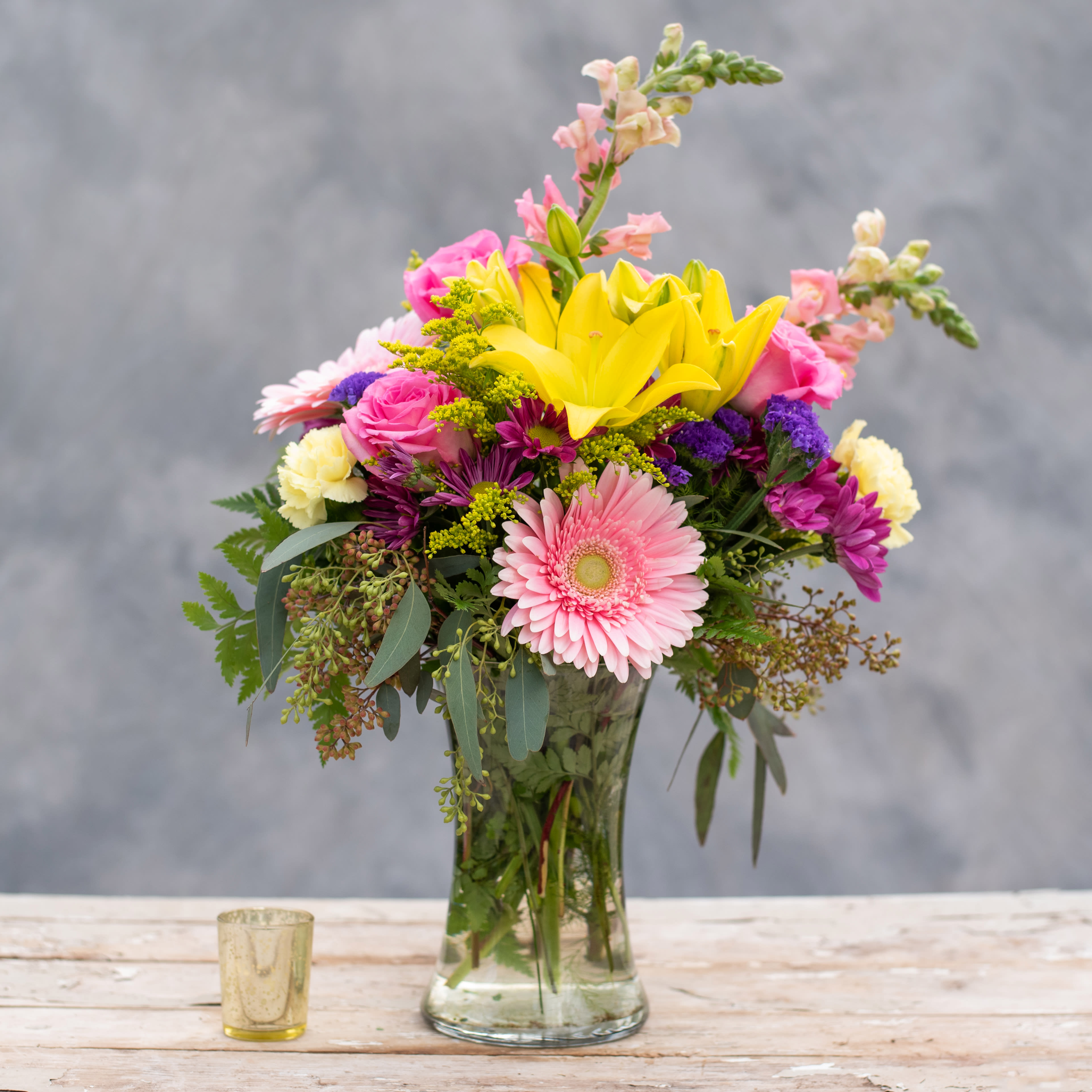 Pink Lemonade - As refreshing as sipping on a tall glass of pink lemonade, this beautiful arrangement with pink snap dragons, roses and gerbera daisies as well as yellow lilies and carnations accented with premium greens will look great on your deck, porch, or sunroom as you relax at the end of a long day! 