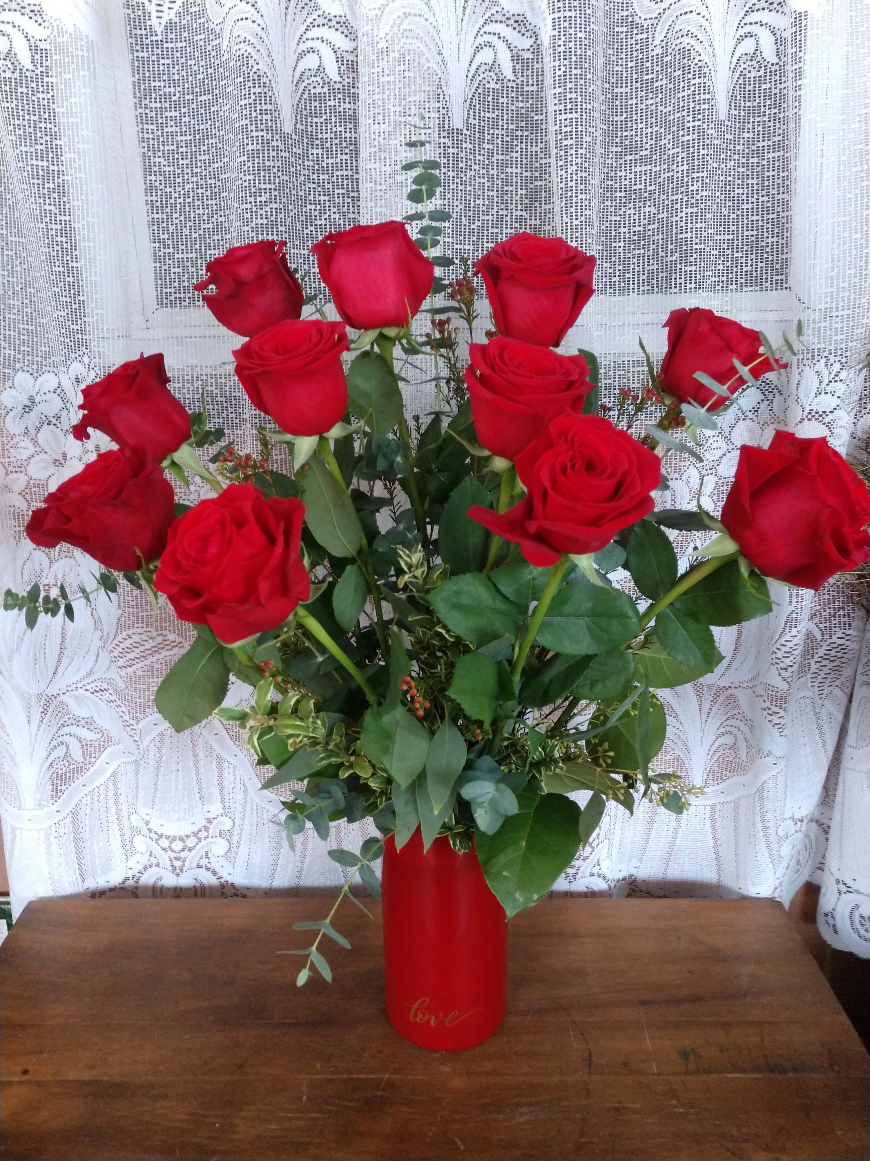 Red Hot Love - Perfectly romantic, these rich red roses arranged in a red glass cylinder vase with love painted on in gold, will be sure to get them all a glow!
