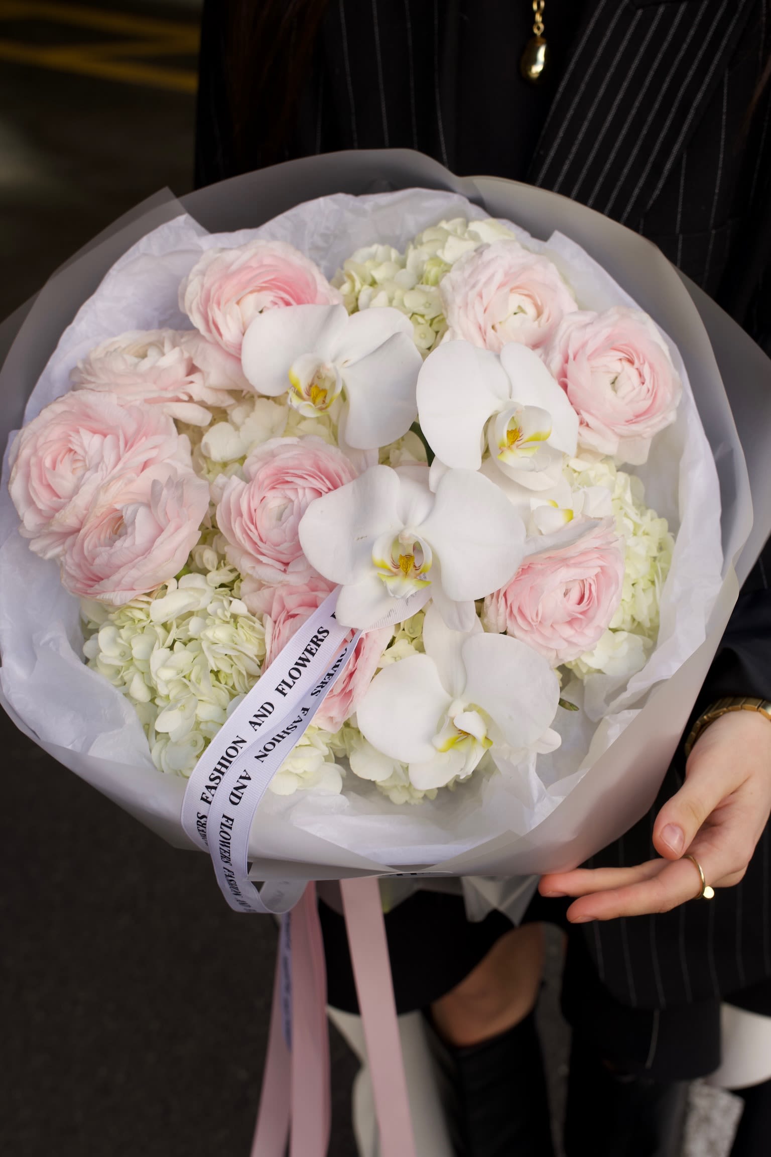 Blush Signature - An airy couture-style bouquet featuring blush ranunculus, white phalaenopsis orchids, and soft hydrangea, wrapped in translucent paper with signature ribbon detailing.   Perfect for bridal showers, weddings, engagement celebrations, baby showers, anniversaries, birthdays, and refined thank-you gestures.   Ideal for those who appreciate soft tones. A beautiful choice for meaningful moments, gentle emotions, and elevated everyday gifting.