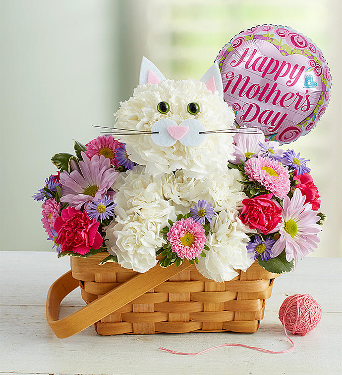 Fabulous Feline for Mom - The cat’s out of the bag - we’ve got the cutest gift for Mom this year! We’ve crafted our floral feline from a mix of white, pink and purple blooms inside a charming, handled basket. Finished off with a fun Mother’s Day balloon, this truly original kitten is sure to leave her smitten.  One-sided arrangement with white carnations, pink Matsumoto asters, lavender daisy poms, hot pink mini carnations and purple monte casino; accented with assorted greenery Crafted in the shape of a cat, complete with ears, eyes and mouth with whiskers Artistically designed in a 7”L handled basket Arrangement measures approximately 11"H x 11"W Includes 18"D Mylar “Happy Mother’s Day!” balloon We hand-design each arrangement, so colors, varieties, container and balloon may vary due to local availability