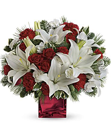 Caroling In The Snow  - Filled with holiday charm. Red spray roses and white Asiatic lilies are arranged to perfection in our red mirrored cube. Red spray roses, white asiatic lilies, and red carnations are accented by tips of white pine, noble fir, and holly. Delivered in red mirrored cube.